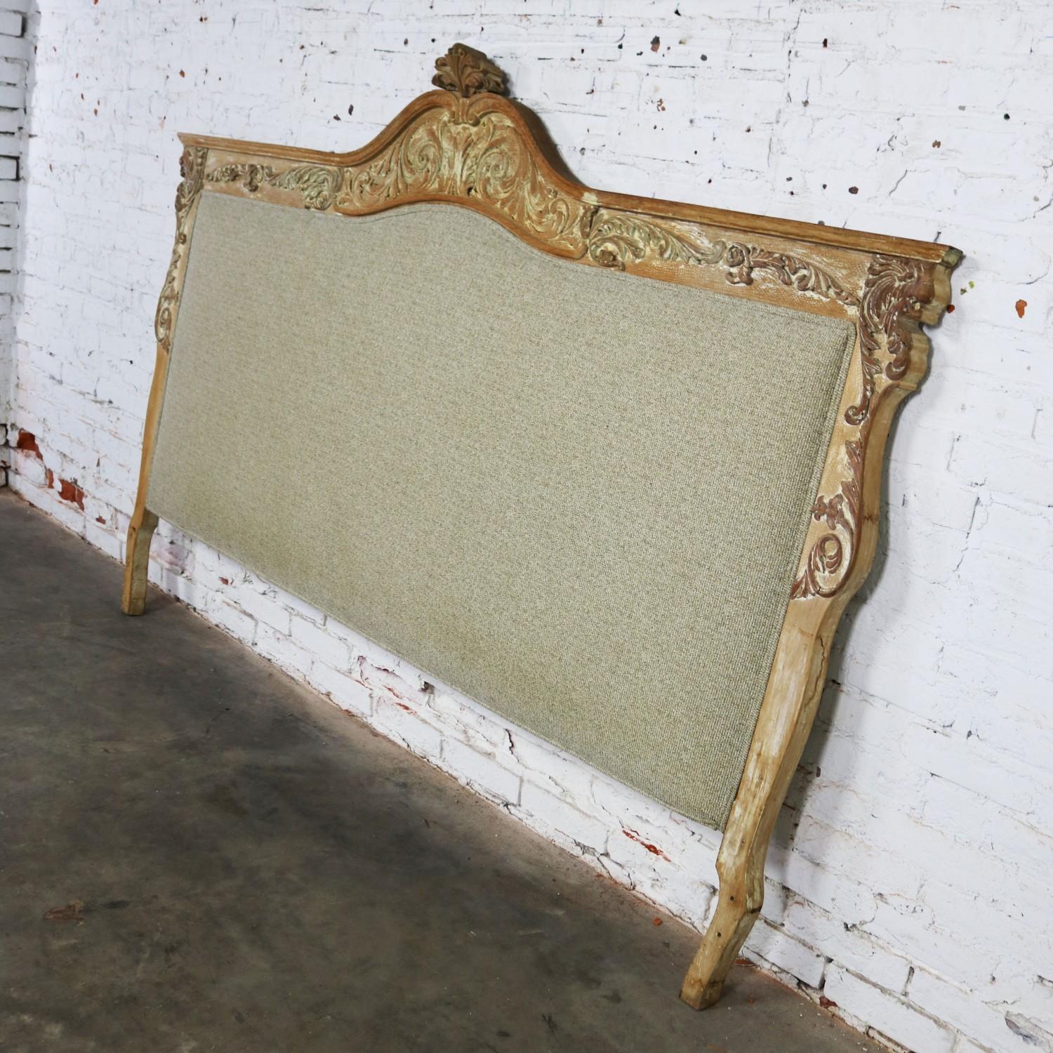 Very handsome Baroque king size headboard with carved lion heads. It is upholstered with ecru colored tweed-like fabric and has a whitewashed finish to the carved wood frame. It is in fabulous ready to use condition. The fabric is awesome, and the