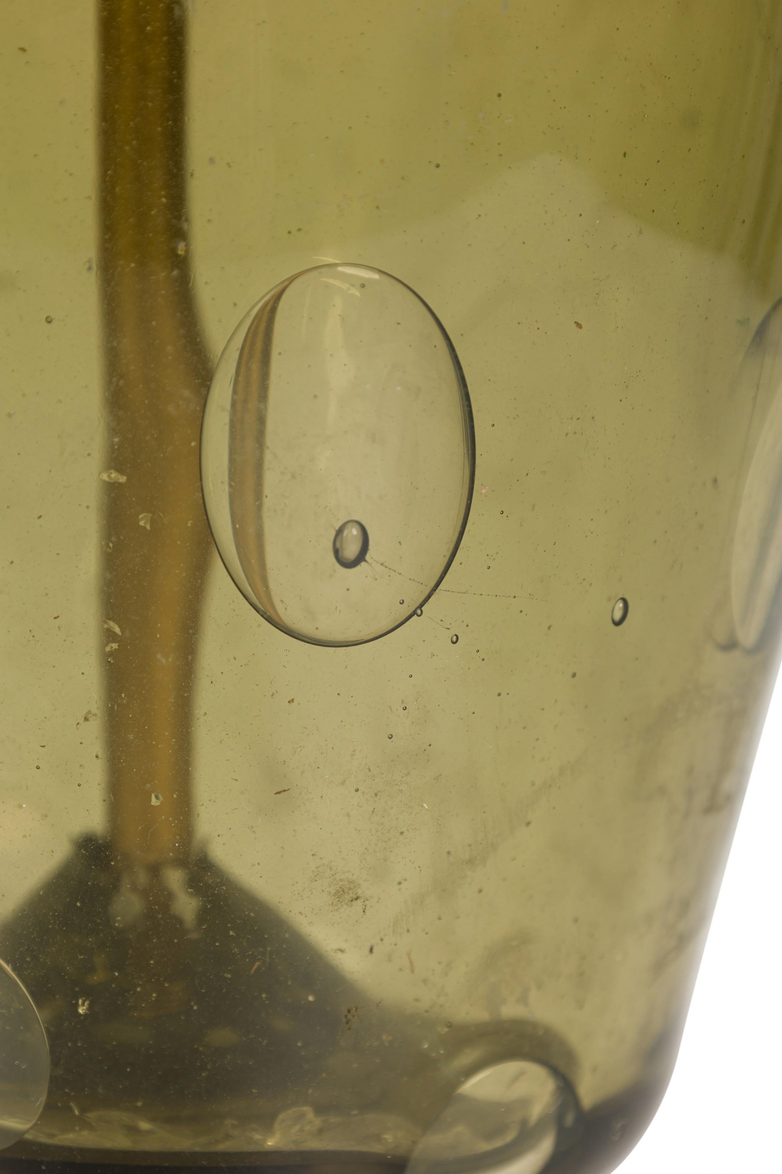 Lampe de table italienne du milieu du siècle en verre vert soufflé à la main en forme de sablier, reliée à une tige en laiton et à une prise d'interrupteur non fonctionnelle en forme de coupe dépassant du sommet. Le corps en verre transparent