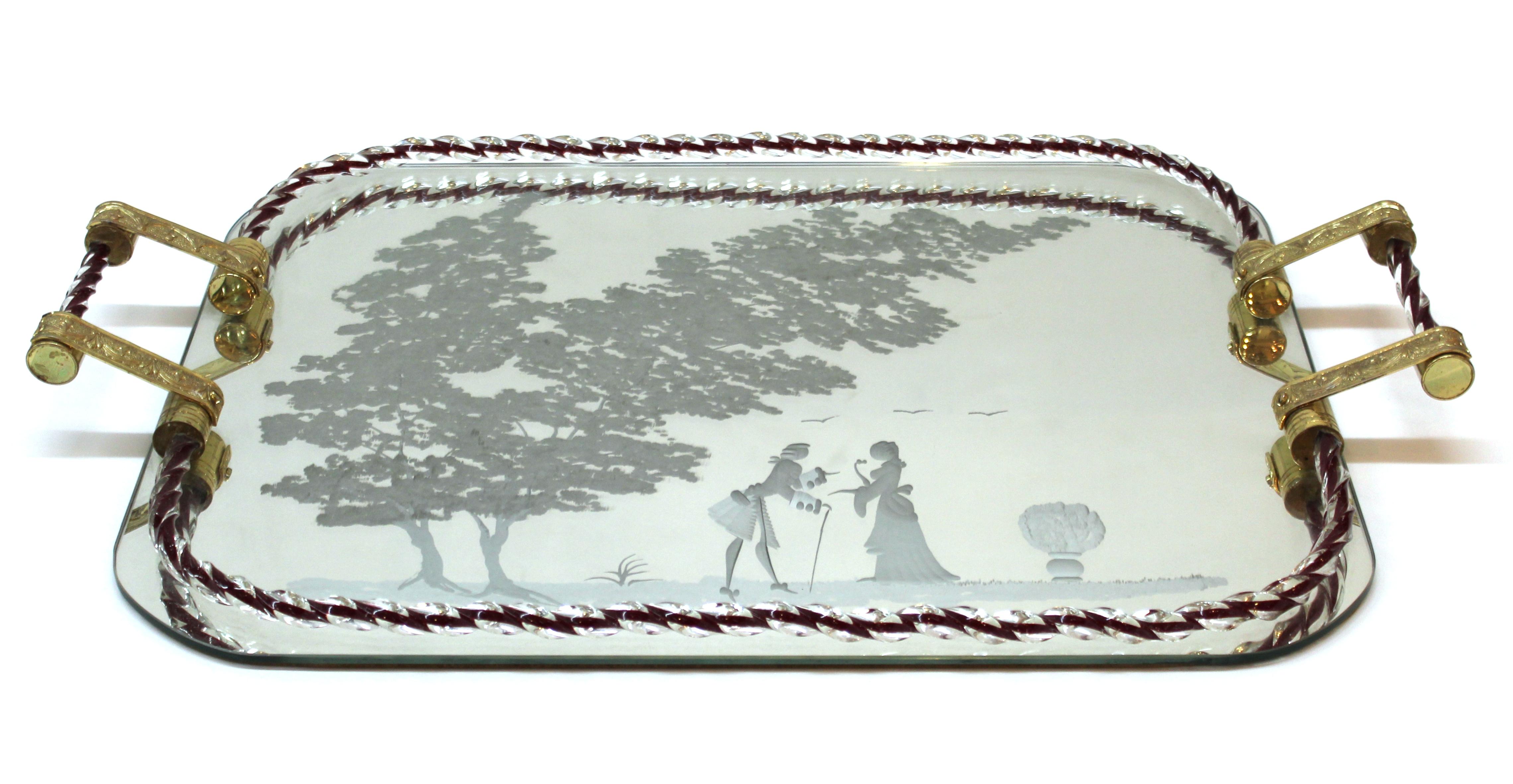 Italian Hollywood Regency serving tray attributed to Ercole Barovier. The piece has a Murano glass gallery and mirrored surface etched with a scene of 18th century lovers and supporting gilt brass handles. Likely made in the 1940s, the piece is in