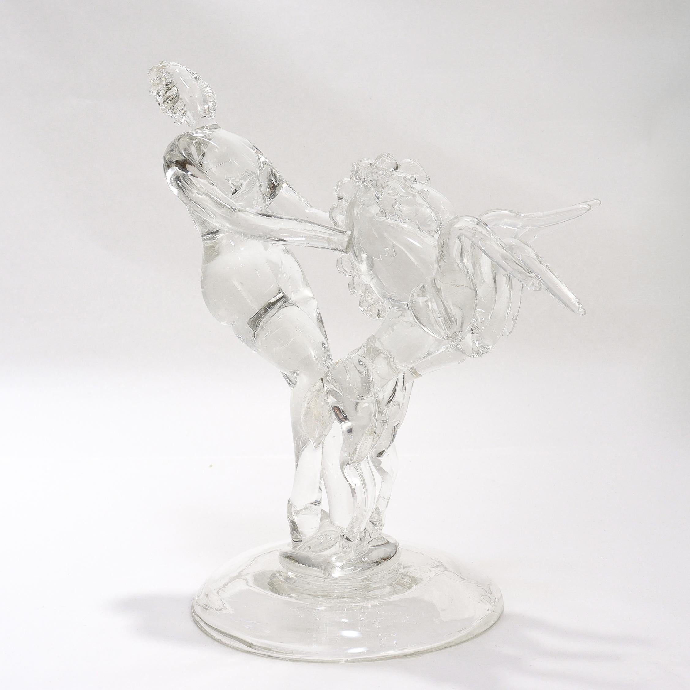 A fine Murano glass figure.

Attributed to Barovier Seguso & Ferro (Seguso Vetri D'arte).

Model 13341. (S.A.I.A.R. model no. 685)

In the form of a stylized nude woman with two rearing horses. 

In clear glass with small gold fleck inclusions in