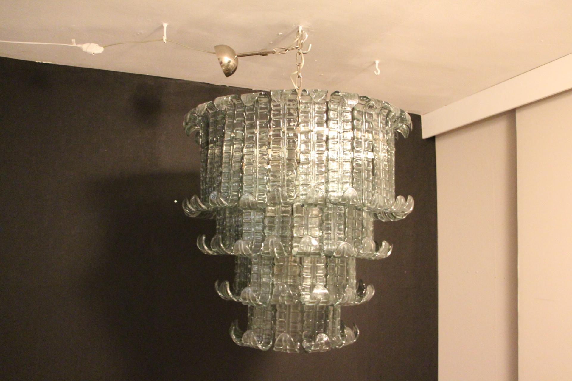 This beautiful chandelier features 71 Murano glass textured palmettes in a Fontana Arte Color going from green to blue .Each piece of glass has been made individually in Murano.
It is a 4 tiers light.
It gives a warm and pleasant light and