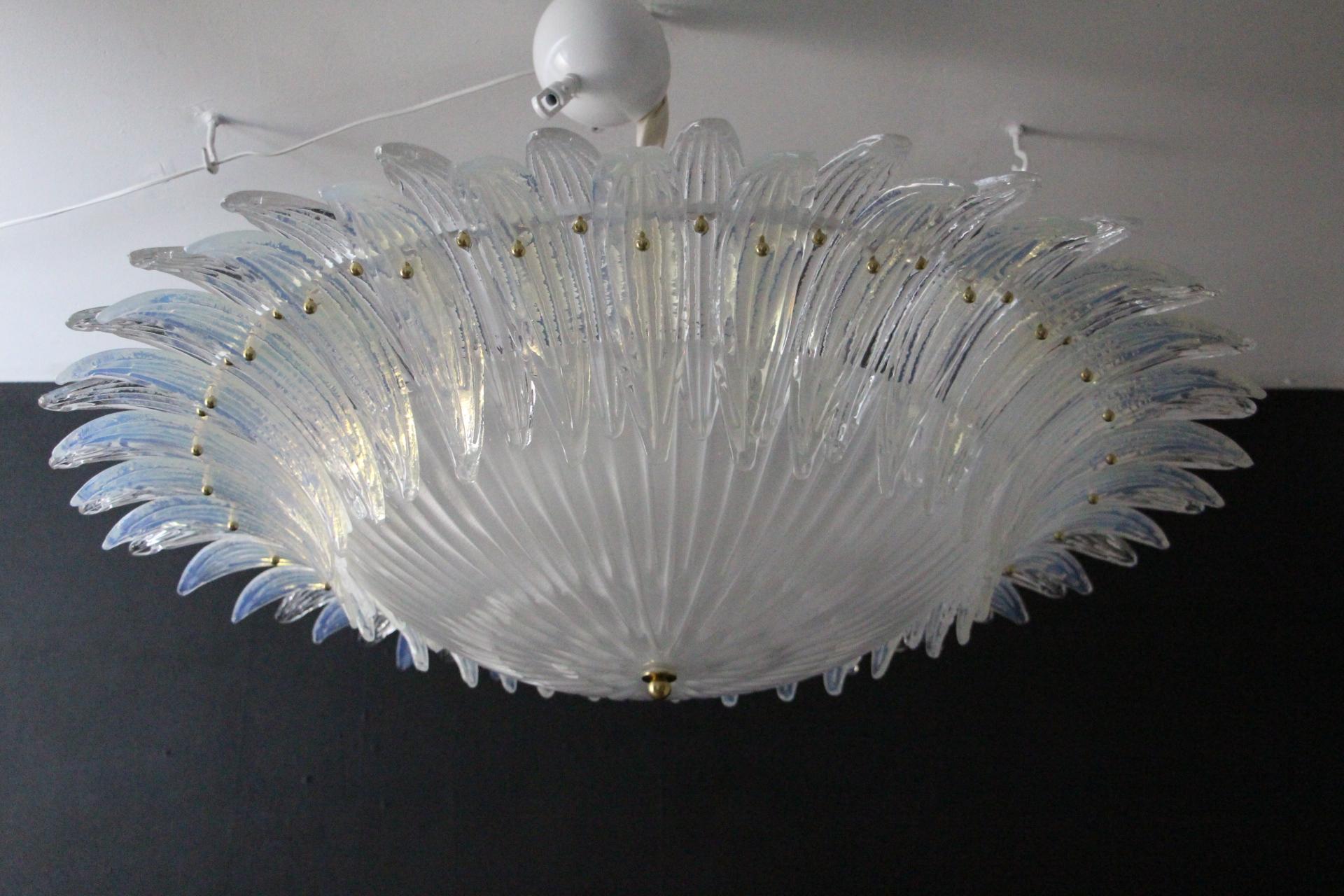 This spectacular chandelier features a large white central glass dome surounded by hand made white and iridescent glass palmettes. Each glass palmette is fixed with a brass stud. Glass palmettes are all textured and have been made by hand