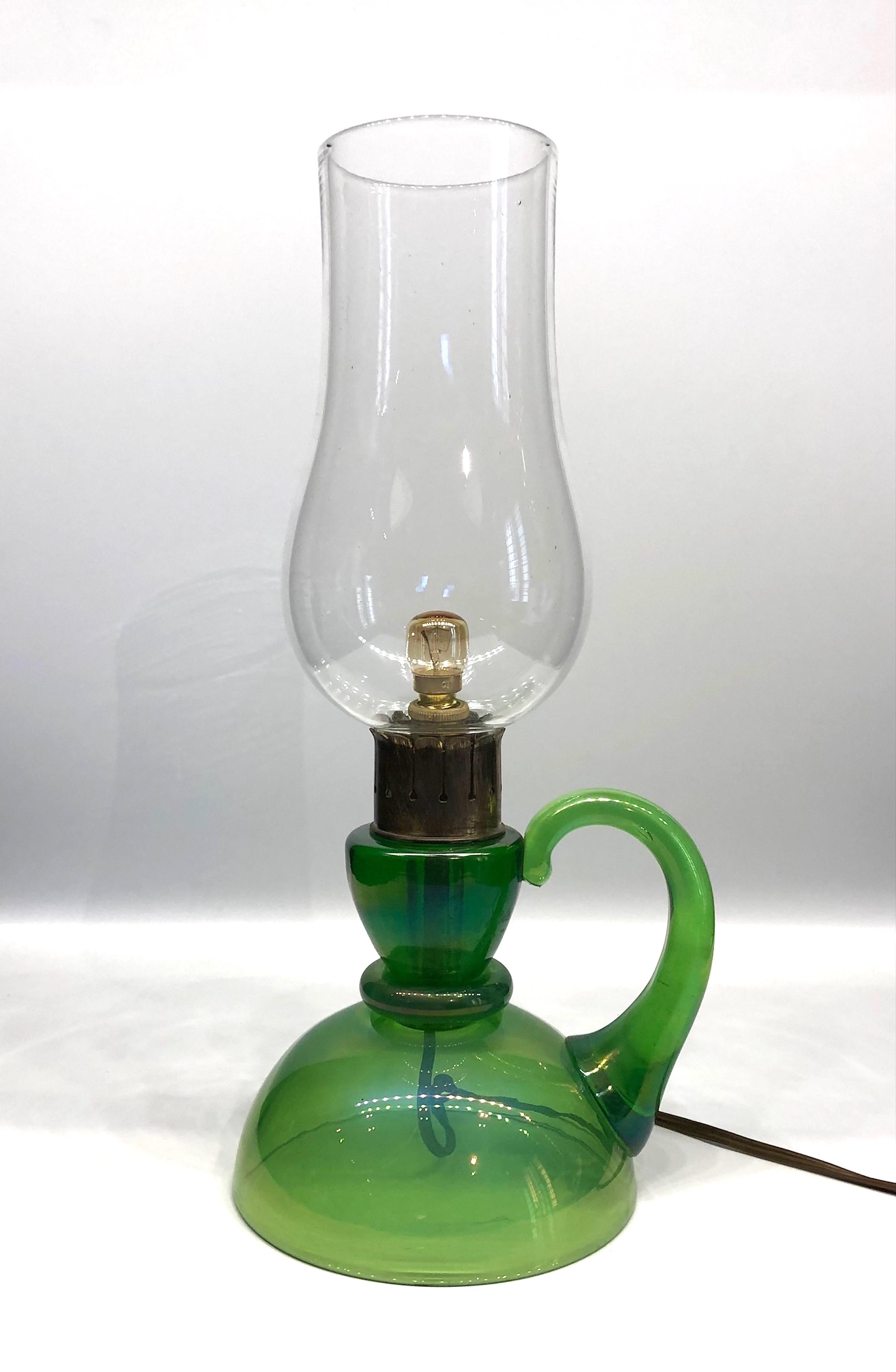 A wonderful and rare 1940s Murano, Italy glass table lamp attributed to the famous glass house of Barovier & Toso. The green glass base and clear glass shade are hand blown with the base having an applied handle. The connecting piece is brass. The