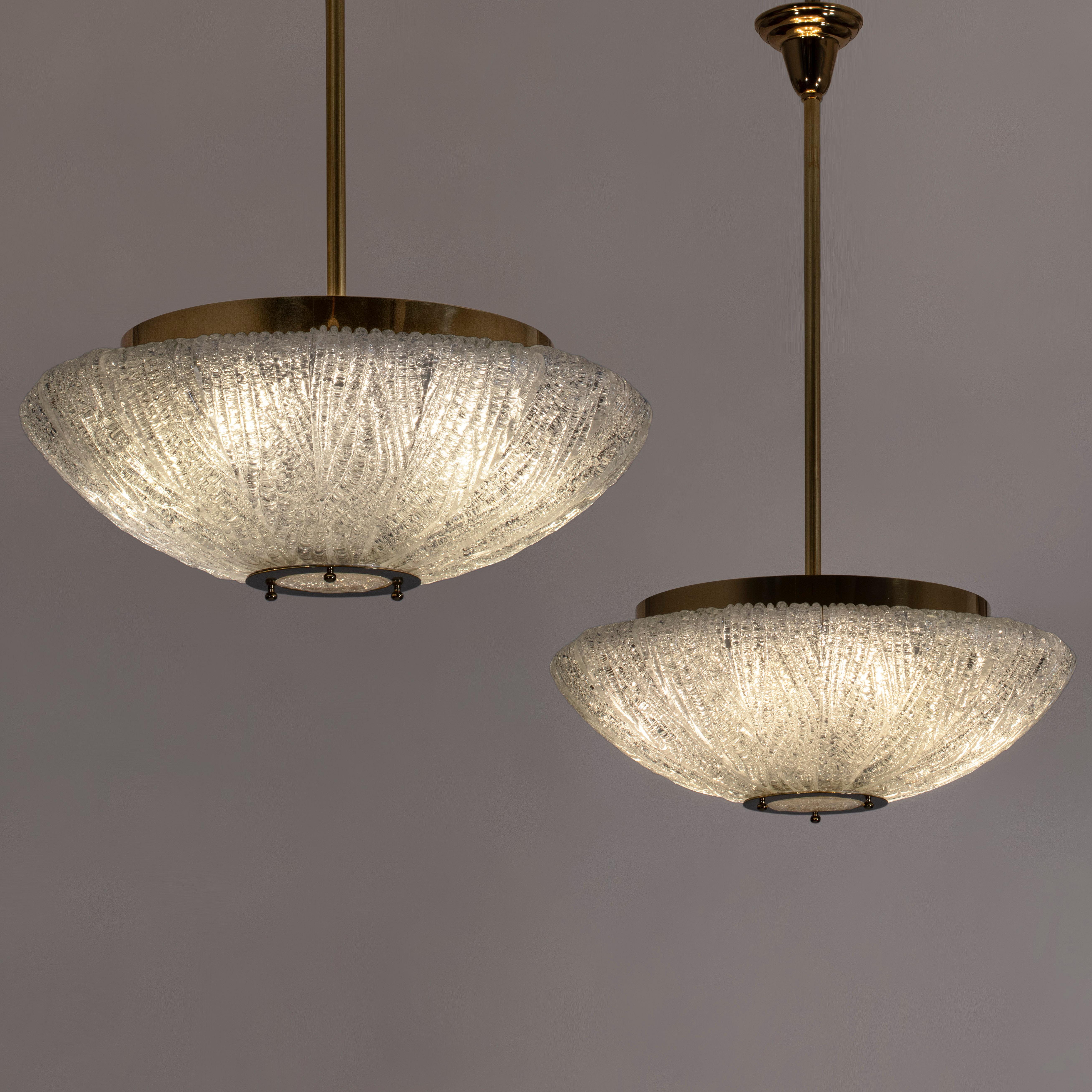 Each circular brass collar, surmounting a colorless Murano glass diffuser composed of rugiadoso glass segments, centering a circular glass medallion within a flat brass ring. 

The height can easily be adjusted. The fixtures can also be flush