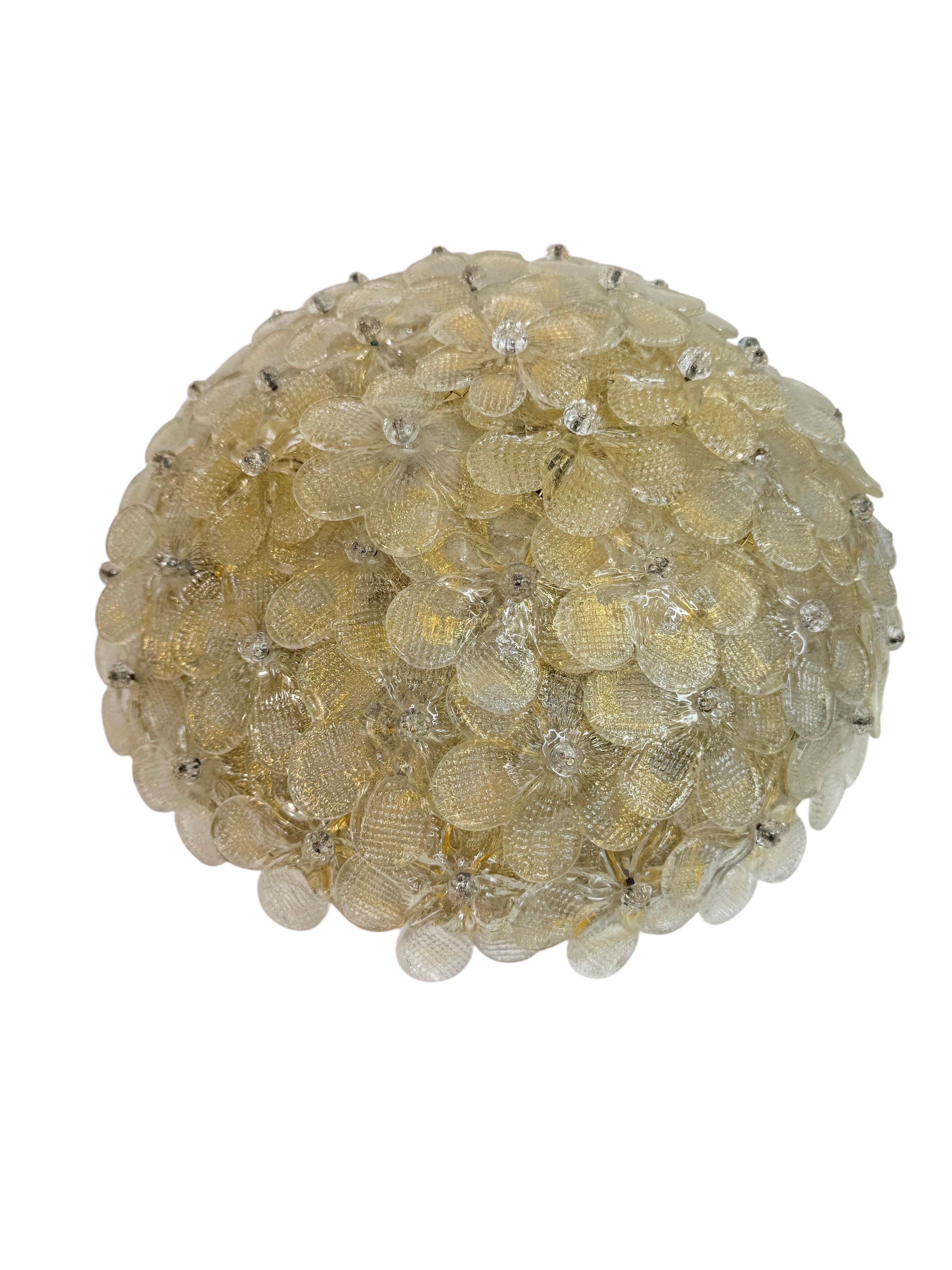 A hand blown Italian flush mount chandelier featuring overlapping crystal flowers, gold with 24-carat gold leaf fleck and clear inclusions, mounted on a basket frame. The Fixture requires three European E27 / 110 Volt Edison bulbs, each bulb up to