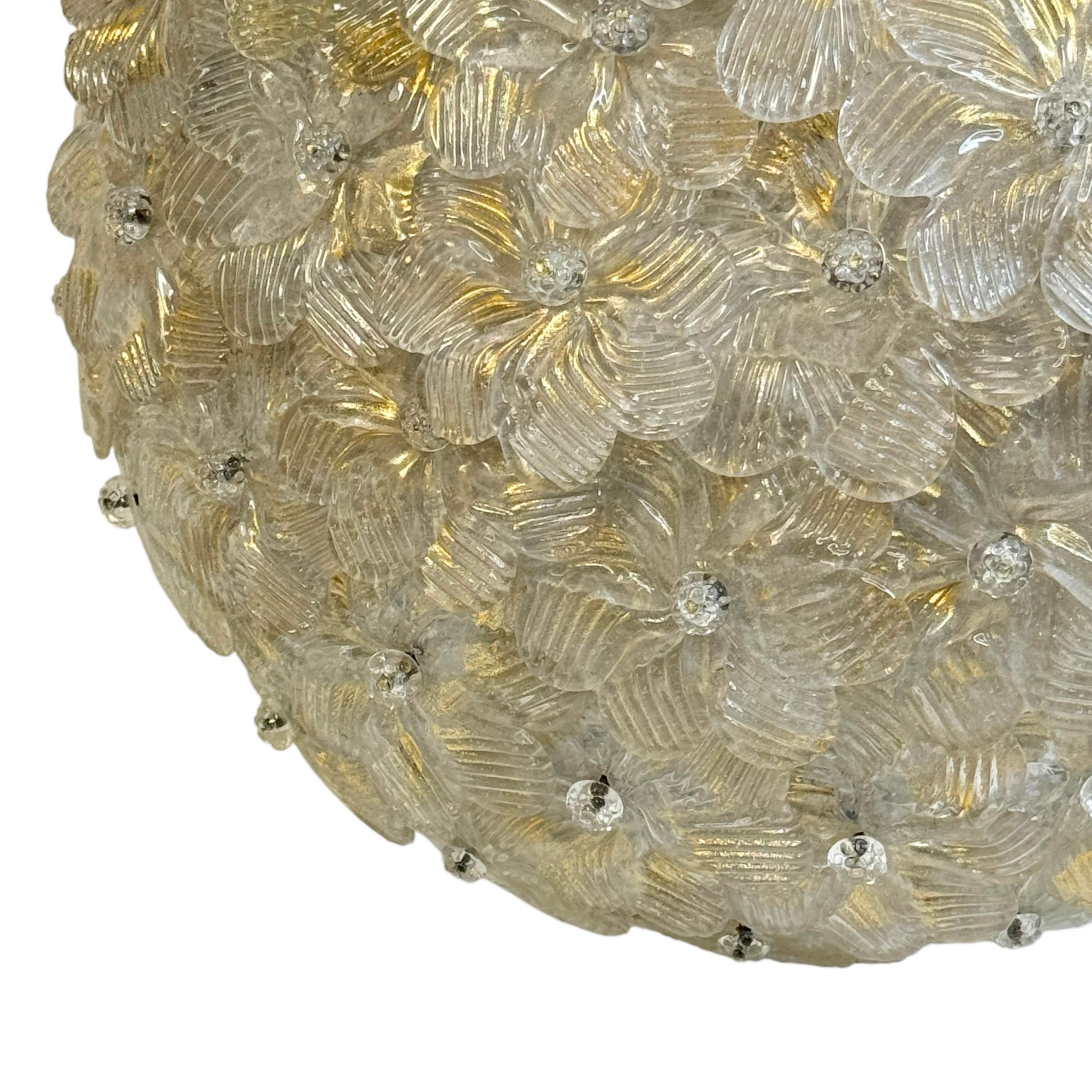 A hand blown Italian flush mount chandelier featuring overlapping crystal flowers, gold with 23-carat gold leaf fleck inclusions, mounted on a basket frame. The fixture requires two European E14 / 110 volt candelabra bulbs, each bulb up to 60 watts.