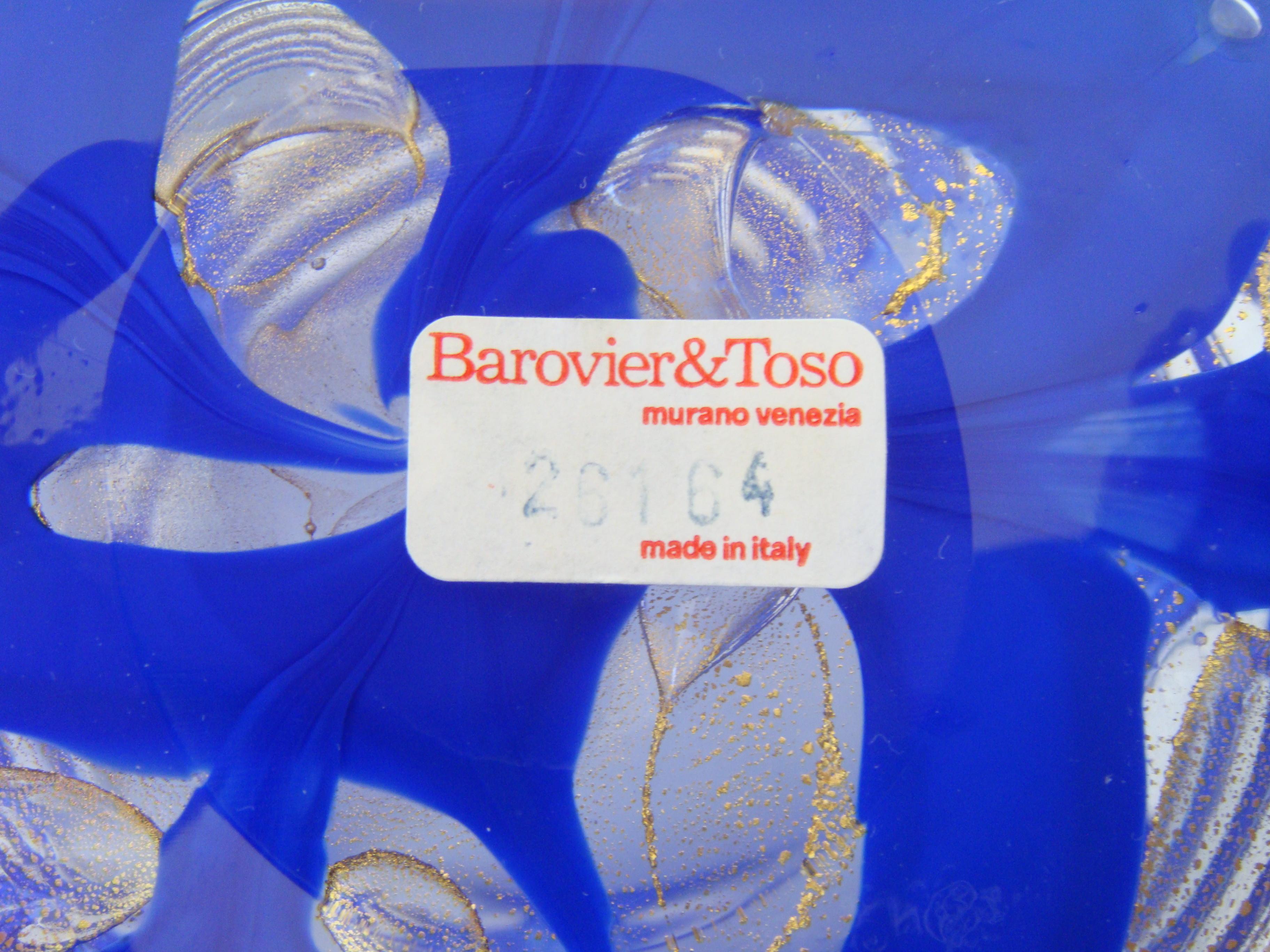 Kräftige Striche in Königsblau, vermischt mit Ösen aus Goldstaub. Auf dem Sockel der Vase sind Barovier und Toso eingraviert, außerdem befindet sich ein Papieretikett mit der Modellnummer. Außerdem ist auf der Oberseite ein durchsichtiges