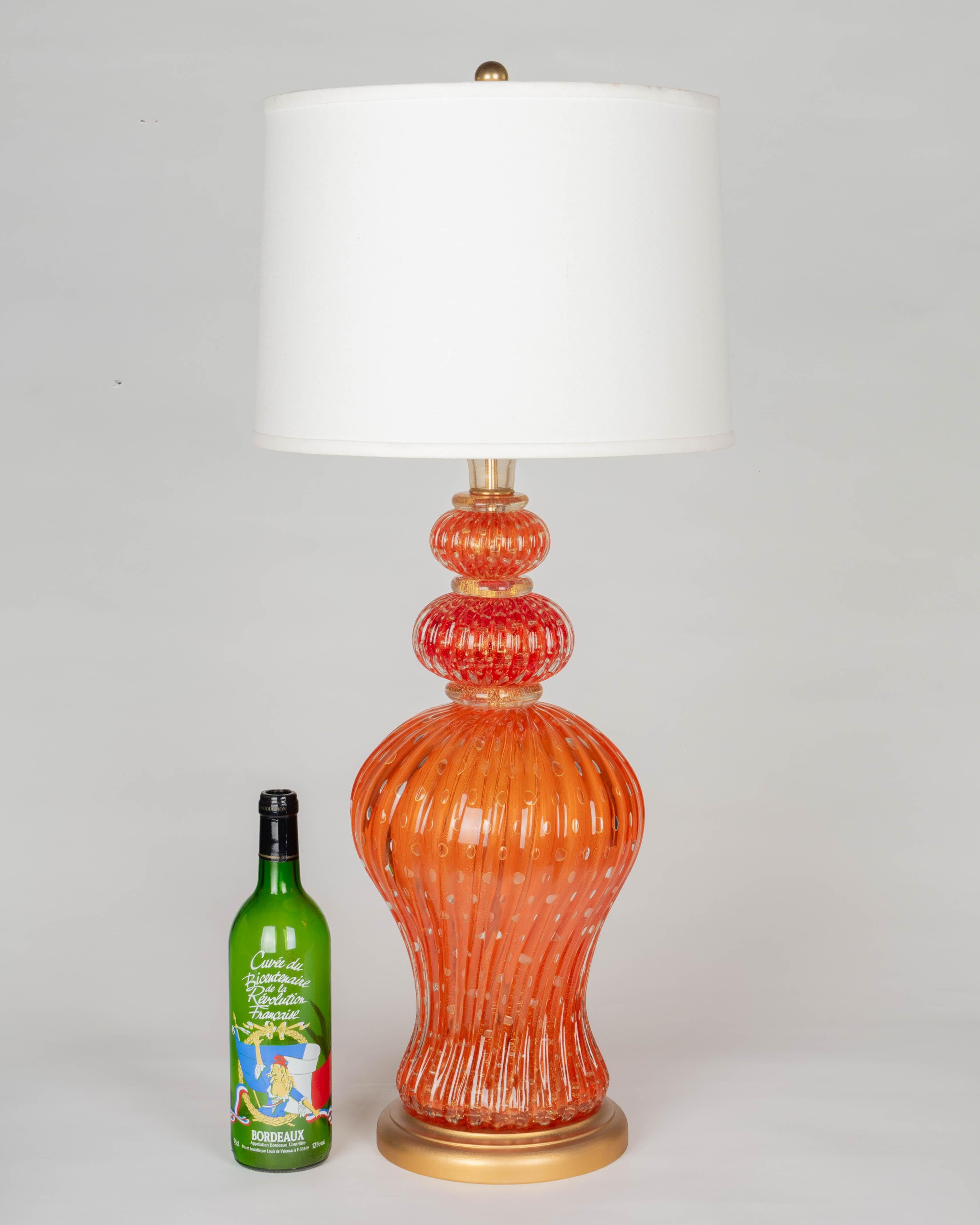 A large Mid Century Murano glass lamp by Barovier & Toso. Hand-blown orange ribbed glass with real gold leaf inclusions and controlled bubbles. Large urn form body with two stacked glass tiers and gold neck. Rare color! New gilt wood base. Rewired