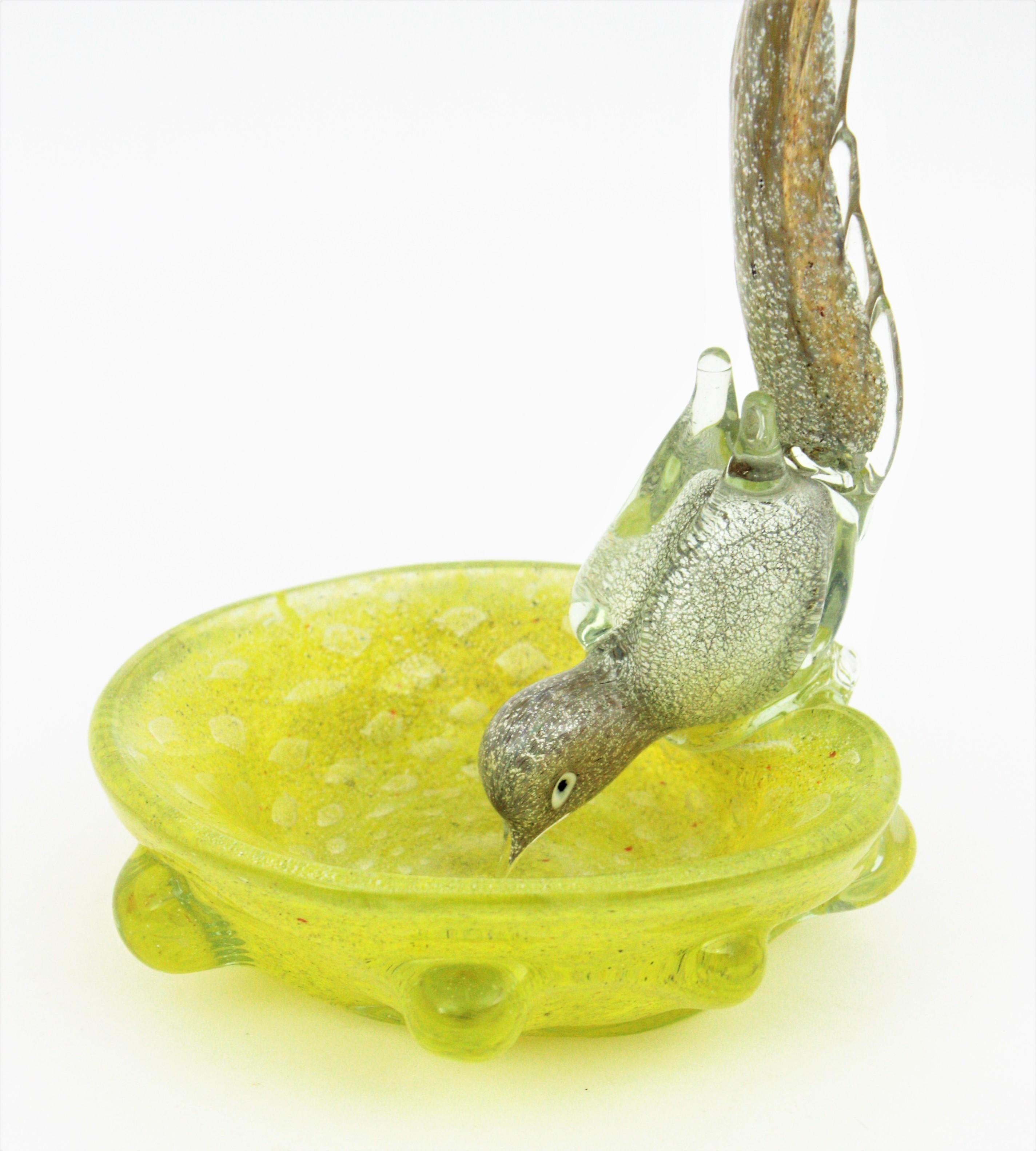 Italian Yellow Murano Art Glass Bird Bowl with Silver Flecks. Attrributed to Barovier e Toso, Italy, 1950s.
Whimsical long tailed drinking bird in clear glass with silver and gold flecks on a controlled bubbles silver flecked yellow Murano glass