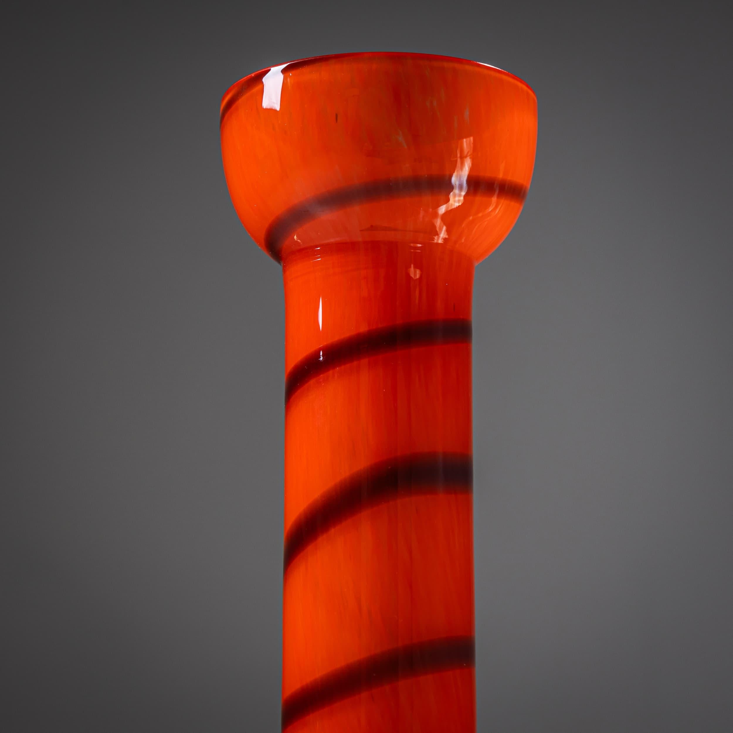 Espressivo vaso da studio della serie B.A.G. (Barovier Art Glass) di Barovier&Toso, Murano, Italia, fine del XX secolo. Realizzato in vetro arancione vibrante con una scia scura a spirale, il pezzo poggia su una base a cupola verde ornata da borchie