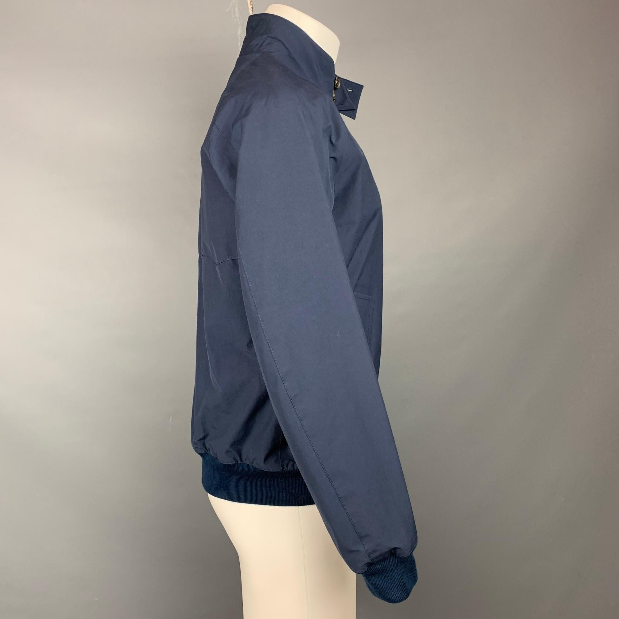 BARRACUDA jacket comes in a navy cotton / polyester with a plaid liner featuring a buttoned collar, ribbed hem, flap pockets, and a full zip up closure. Made in England.

Very Good Pre-Owned Condition.
Marked: 40
Original Retail Price: