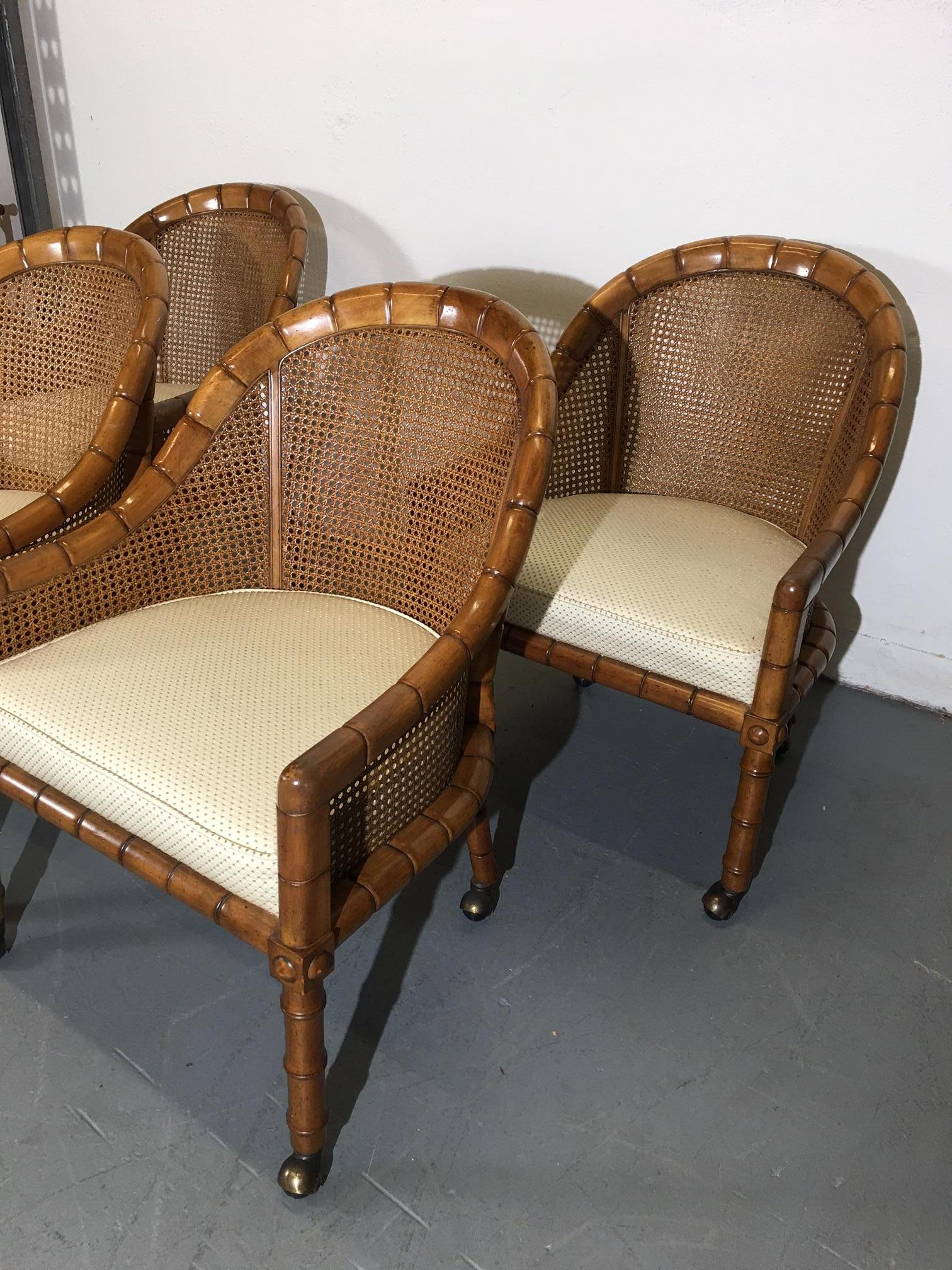 Set of four faux-bamboo-style cane back accent chairs. Original patinated copper-covered casters. Can work as head chairs at the dining table to lounge chairs in the living room.