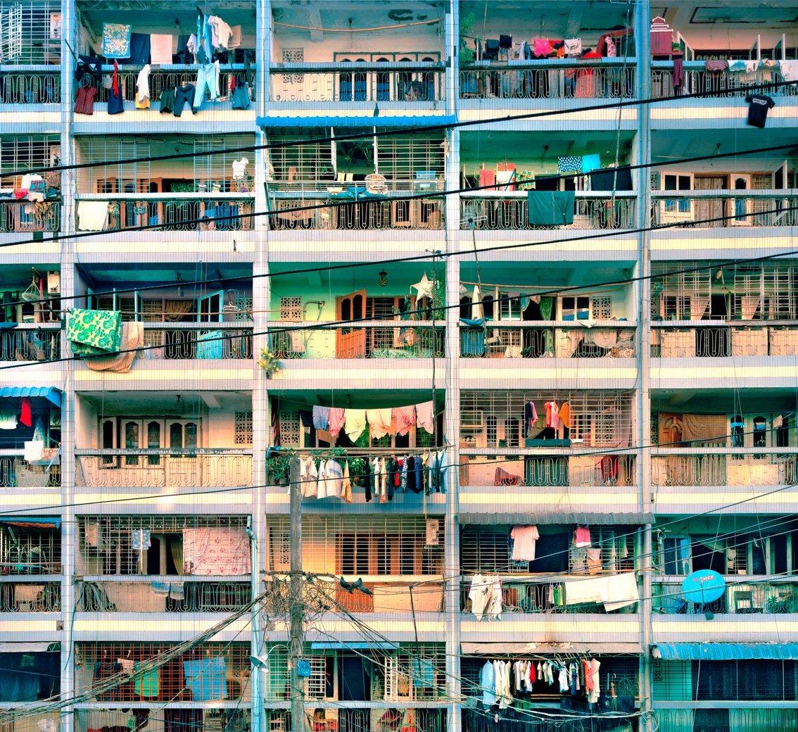 Vita vissuta sul balcone...  I fili del bucato festonano l'ambiente di vita nell'umidità di Yangon, in Birmania.
–
Un tempo la vita in comune nei grattacieli era vista come un grande passo avanti per l'umanità.  La serie Tenement di Cawston cattura