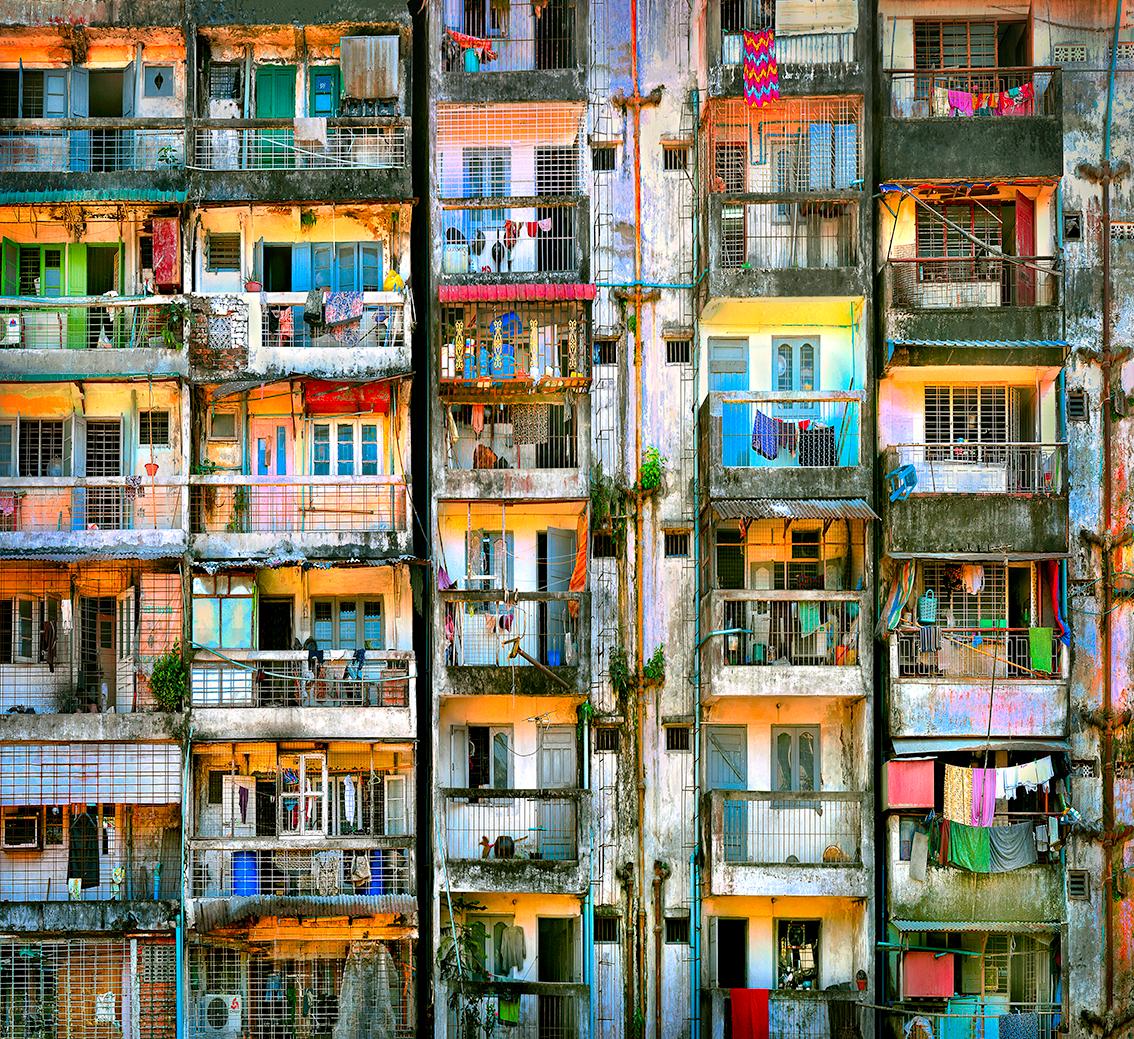 28 Flats -  High rise in Burma
–
High-rise communal living was once seen as a great step forward for mankind.  Cawston’s Tenement series captures the individual within the collective.  By focusing on the repetitive structure it is the anomalies that