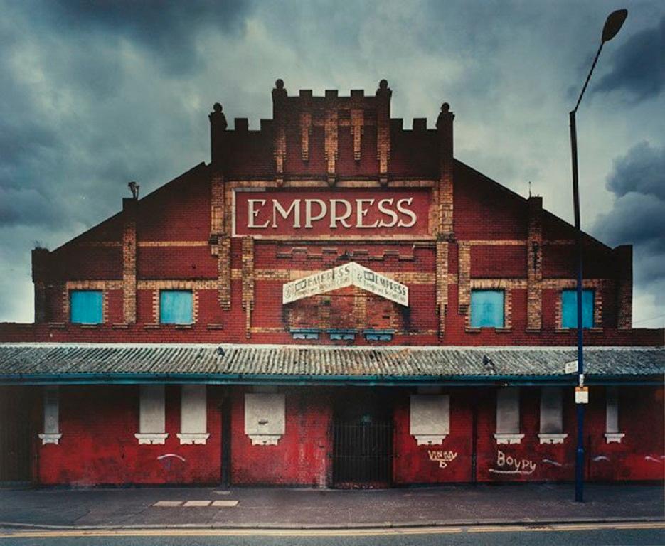 The Empress cinema building in Manchester before its demise
–
Cawston’s Concrete Jungle is not a vision of the ultramodern, of orderly skyscrapers with comfortable interiors.  It is rather of a Blade Runneresque postmodern world where the process of