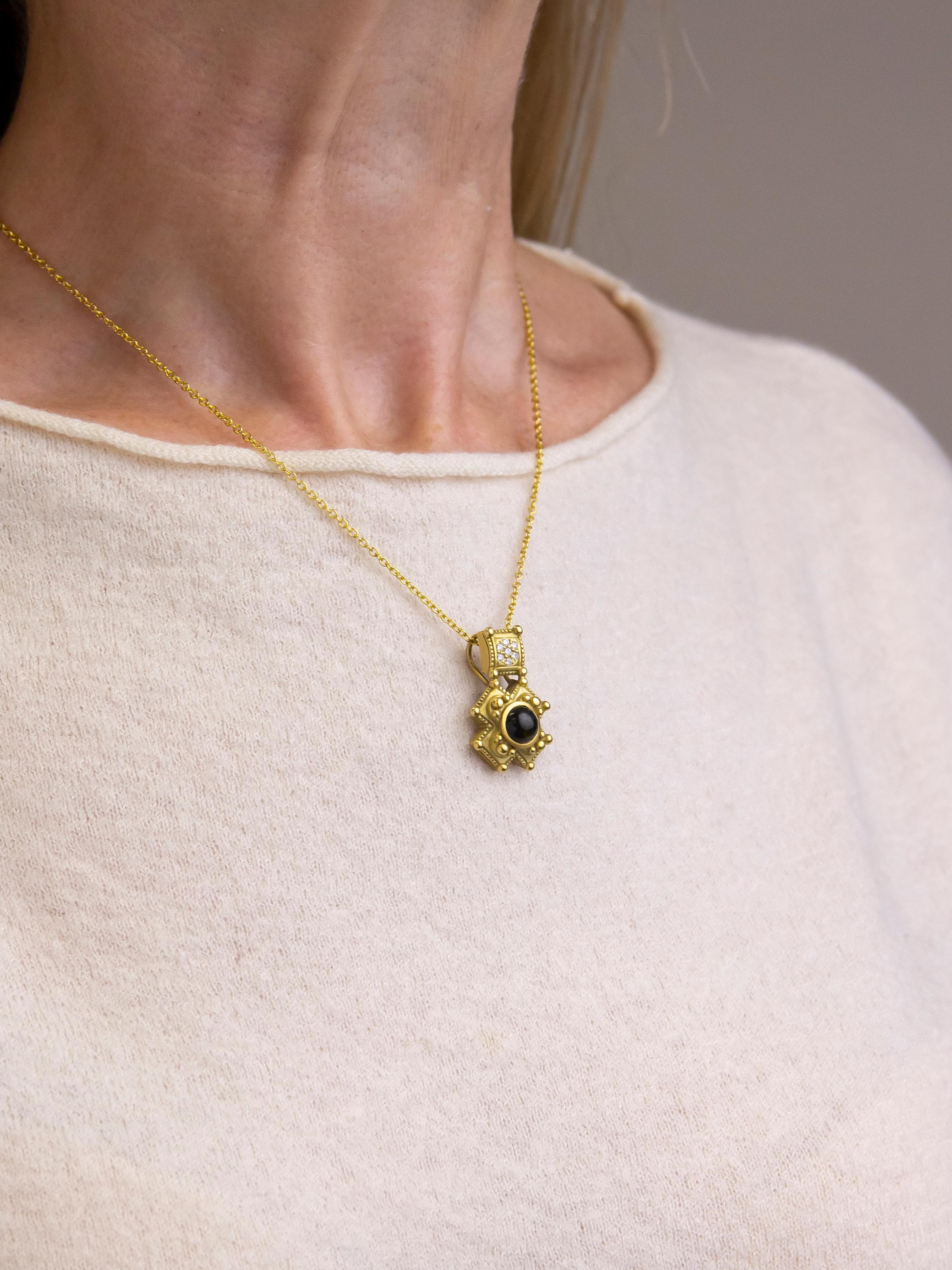 Crafted from 18 karat yellow gold, this pendant is a design by American jeweller Barry Kieselstein-Cord. The pendant centres on a single cabochon cut green tourmaline which is set in an off centre Maltese cross surrounded by gold granulation. Above