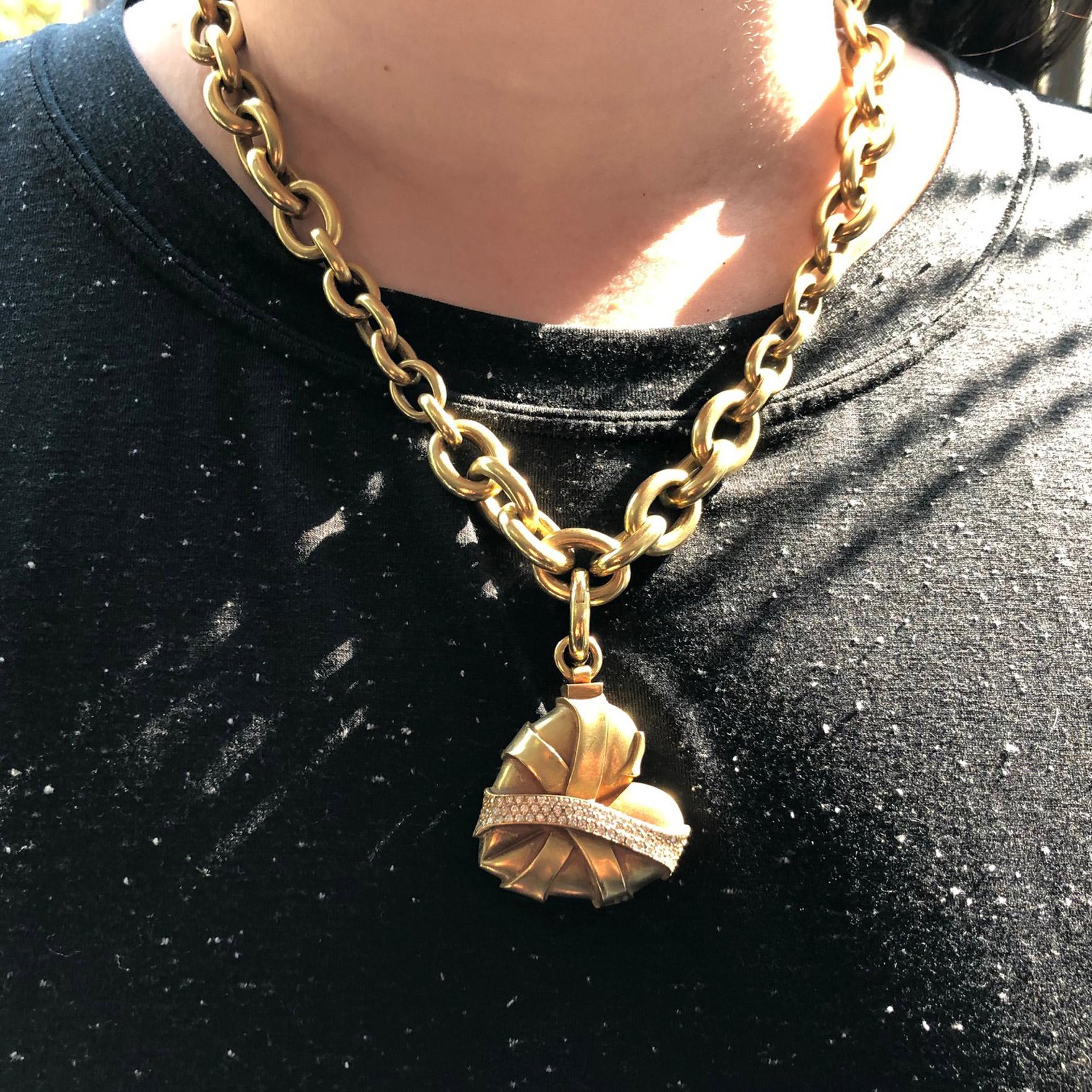 Known for his bold designs, choice of slightly greenish gold and heavy gold work, Barry Kieselstein-Cord has created this iconic heart chain necklace. The beautifully sculptured heart has 3 bands of gold crossing over it with the top one pave set