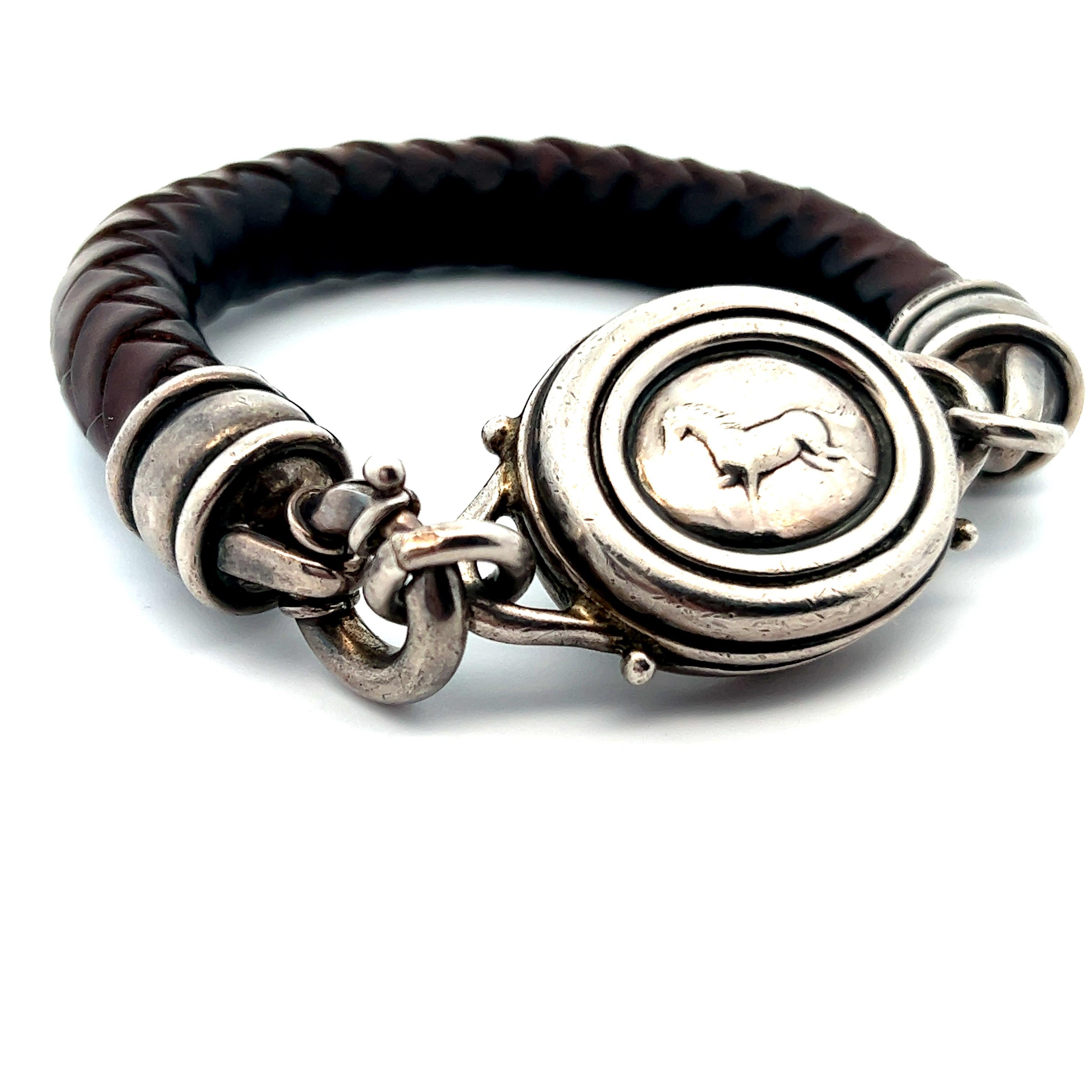 Dieses wunderschöne Armband aus Sterlingsilber von Barry Kieselstein ist aus braunem Leder geflochten und zeigt ein wunderschönes Pferdemotiv. Das Armband hat ein klobiges Design durch das breite Ledergeflecht, das diesem Armband eine beeindruckende