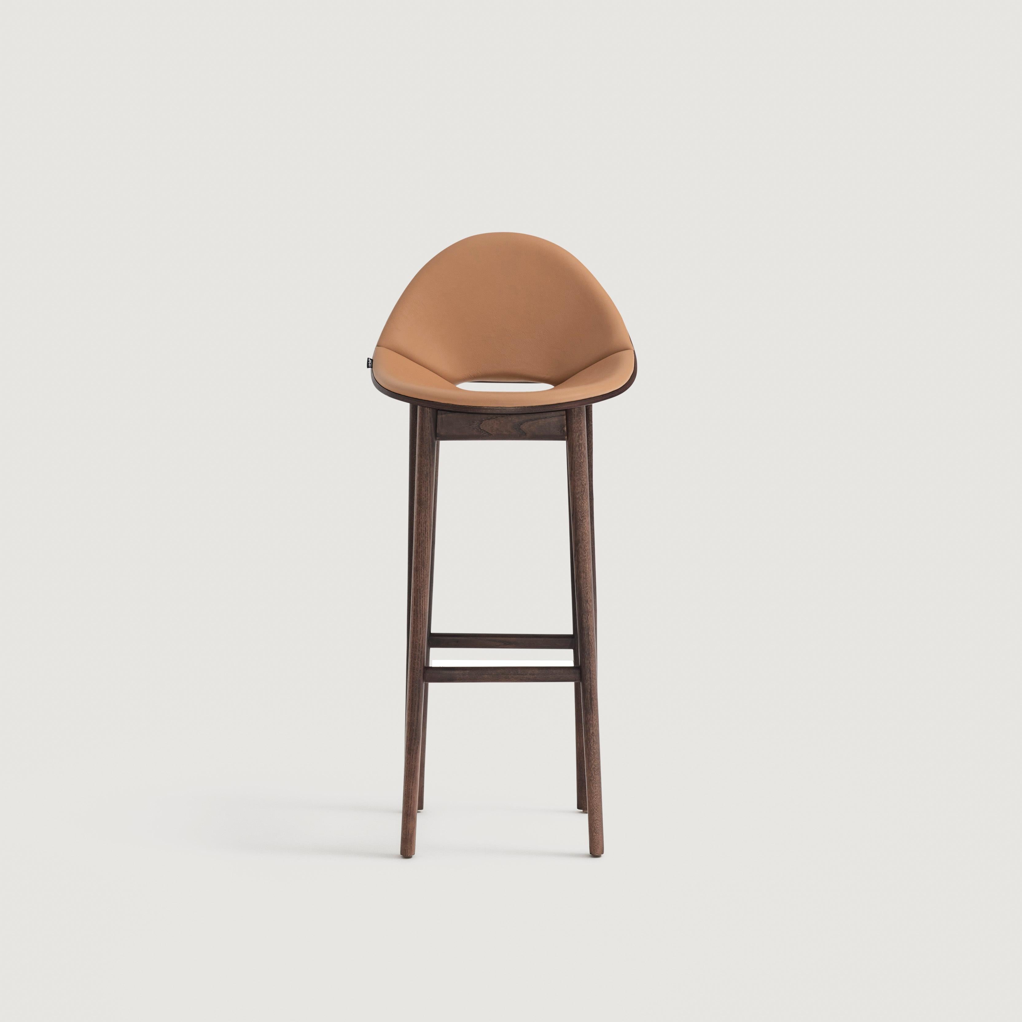This stylish stool features a solid ash wood frame, providing a durable foundation. The upholstered front shell offers a comfortable seating experience, while the wooden back adds a touch of visual interest. The chair's combination of modern and