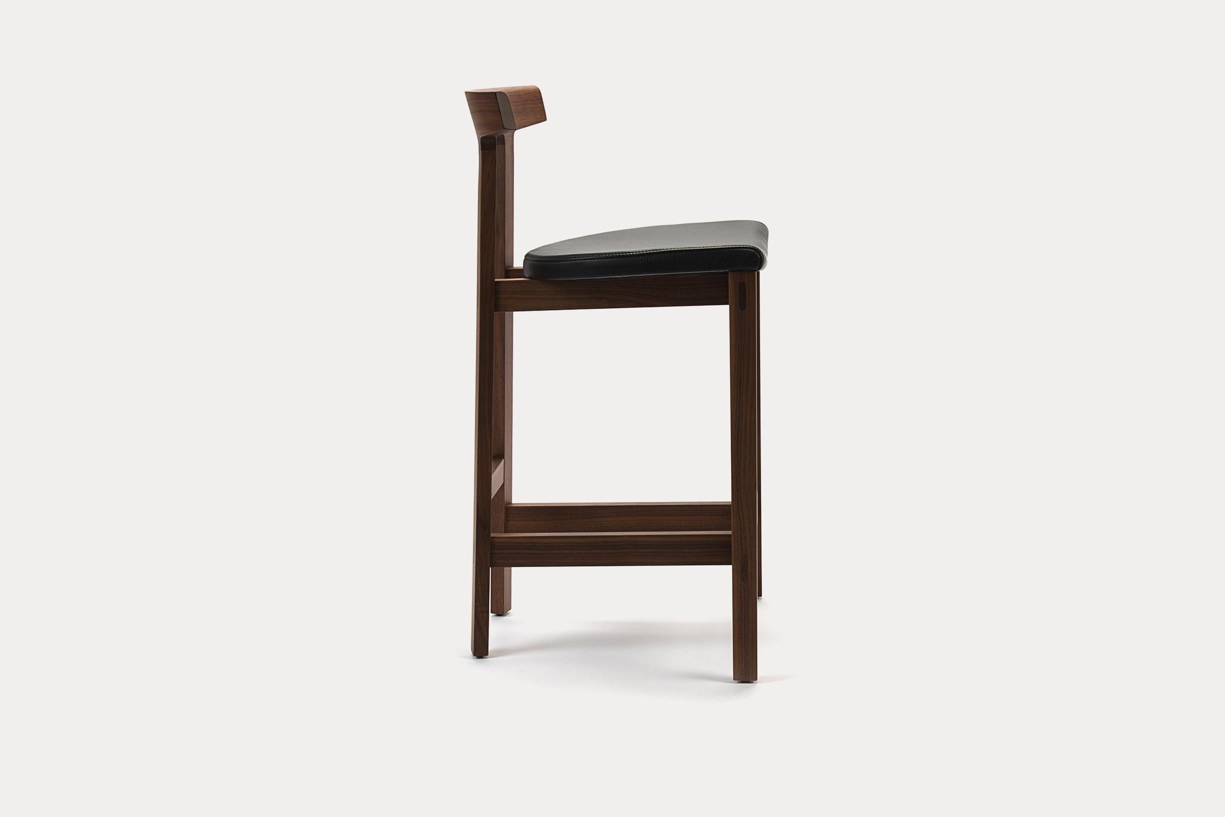 Torii barstool with walnut frame and midnight blue B leather seat. This barstool is a simple yet sophisticated design with an arched back rest. The minimal lines and simple construction offer a surprising amount of comfort and sturdiness. The arched