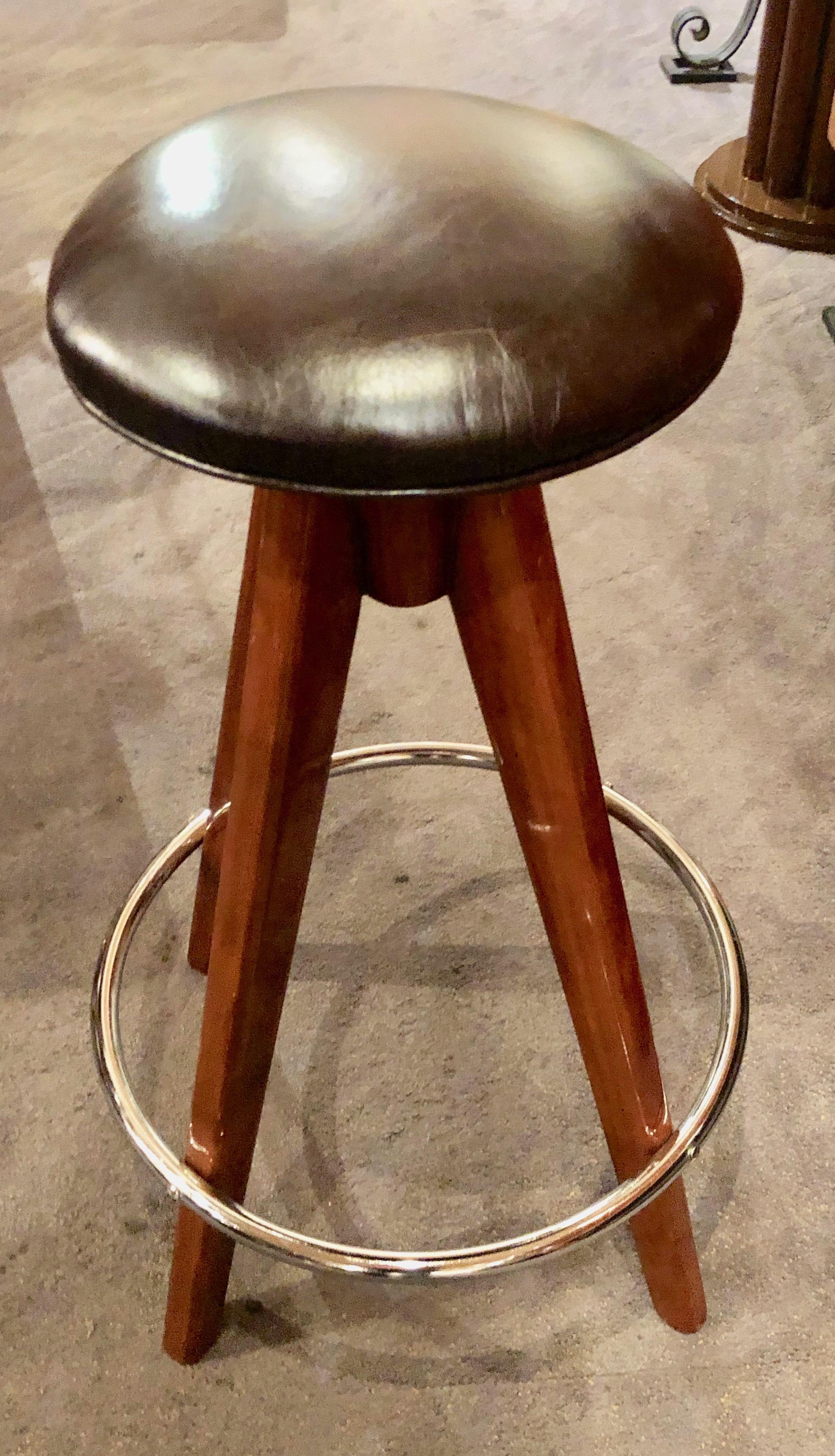 Three matching Art Deco style barstools in tripod shaped wood leg design with chrome band foot rest and brown leather tops. Newly made for our shop of high quality materials and workmanship. Very comfortable could be used in any stand up or stand