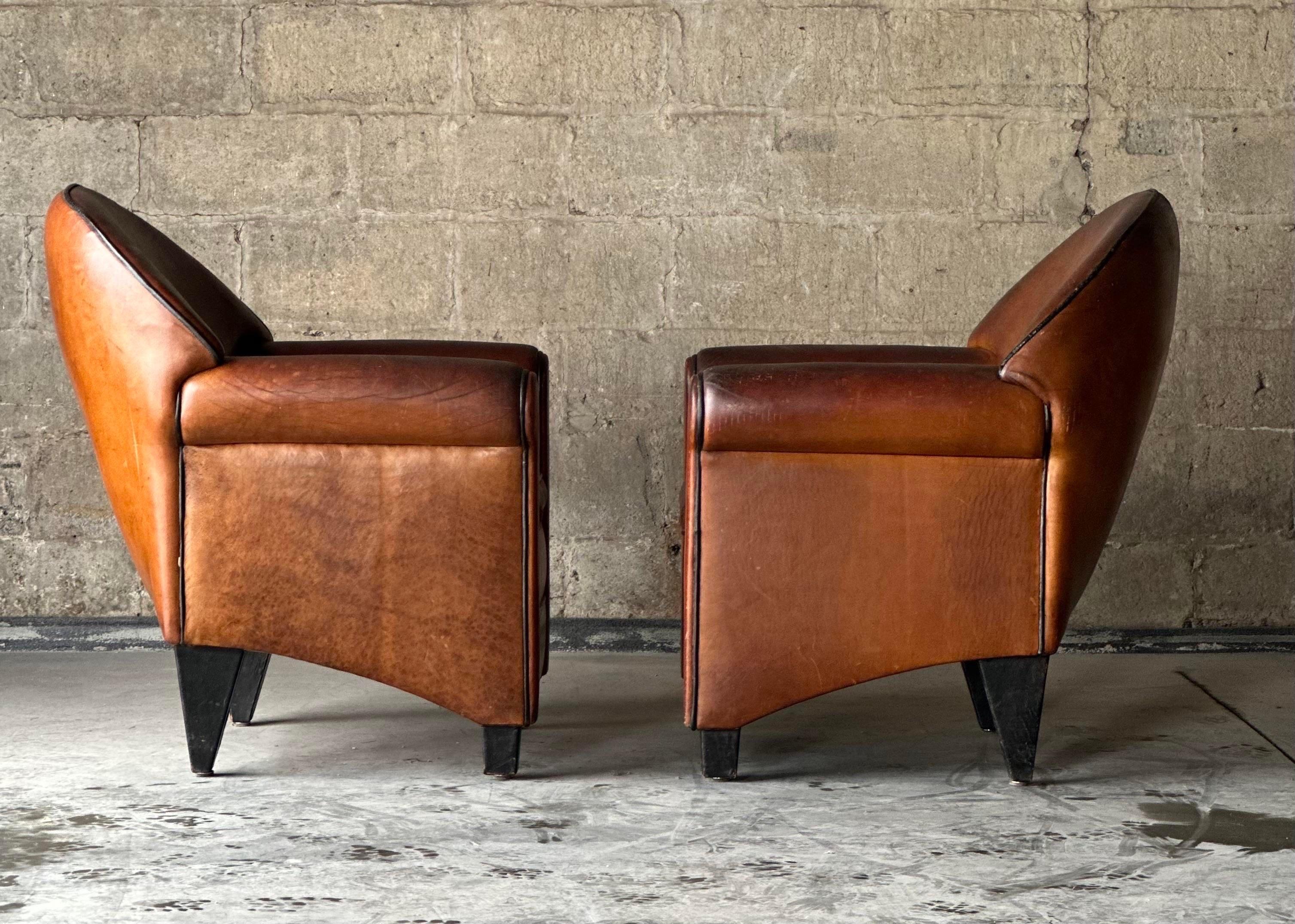A pair of ‘Monet’ Art Deco club chairs by Bart van Bekhoven for Artistiek. Upholstered throughout in brown sheep’s leather, with black leather covered legs.
