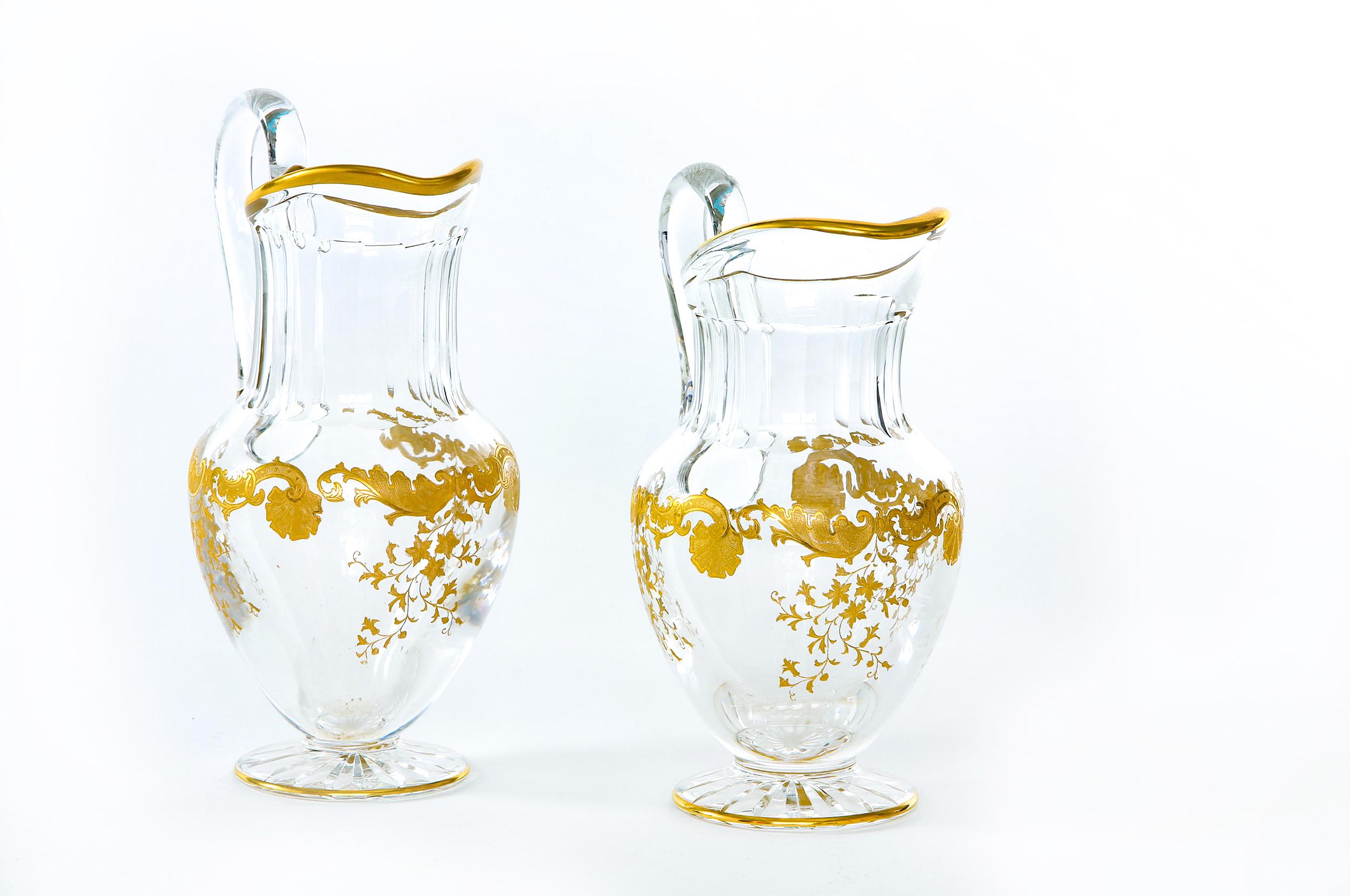 Mid-20th century pair of Saint Louis crystal with gold design details tableware / barware jug pitchers. Each one is in great condition. Maker's mark stamped undersigned. Each one stands about 11 inches tall x 7 inches diameter.
  