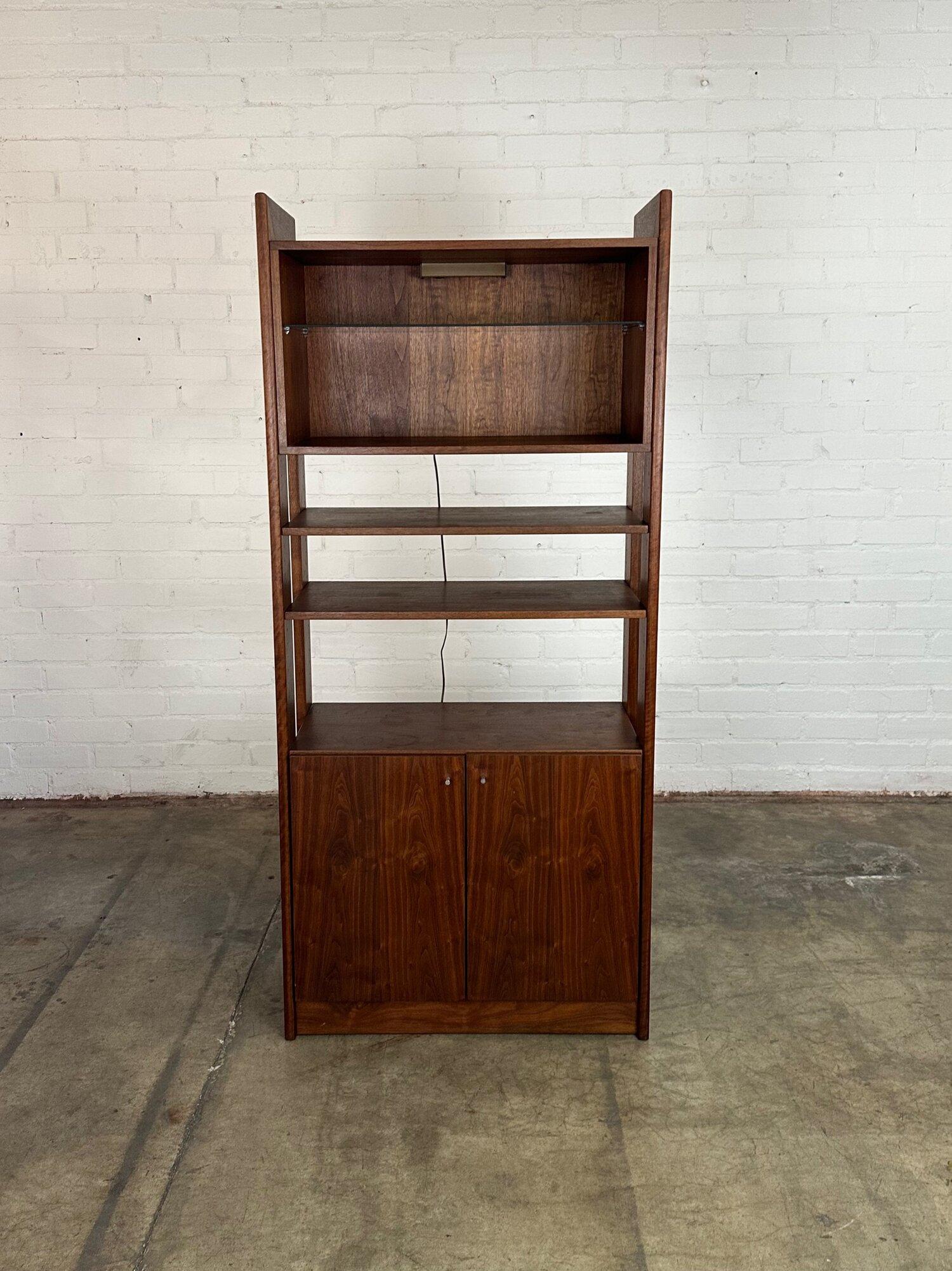 W34 D16 H76

Well preserved walnut free standing bookcase. Item has one fully open compartment with a light on the top portion and one closed portion on the bottom. Shelves are adjustable and removable. Item shows no major areas of wear and is