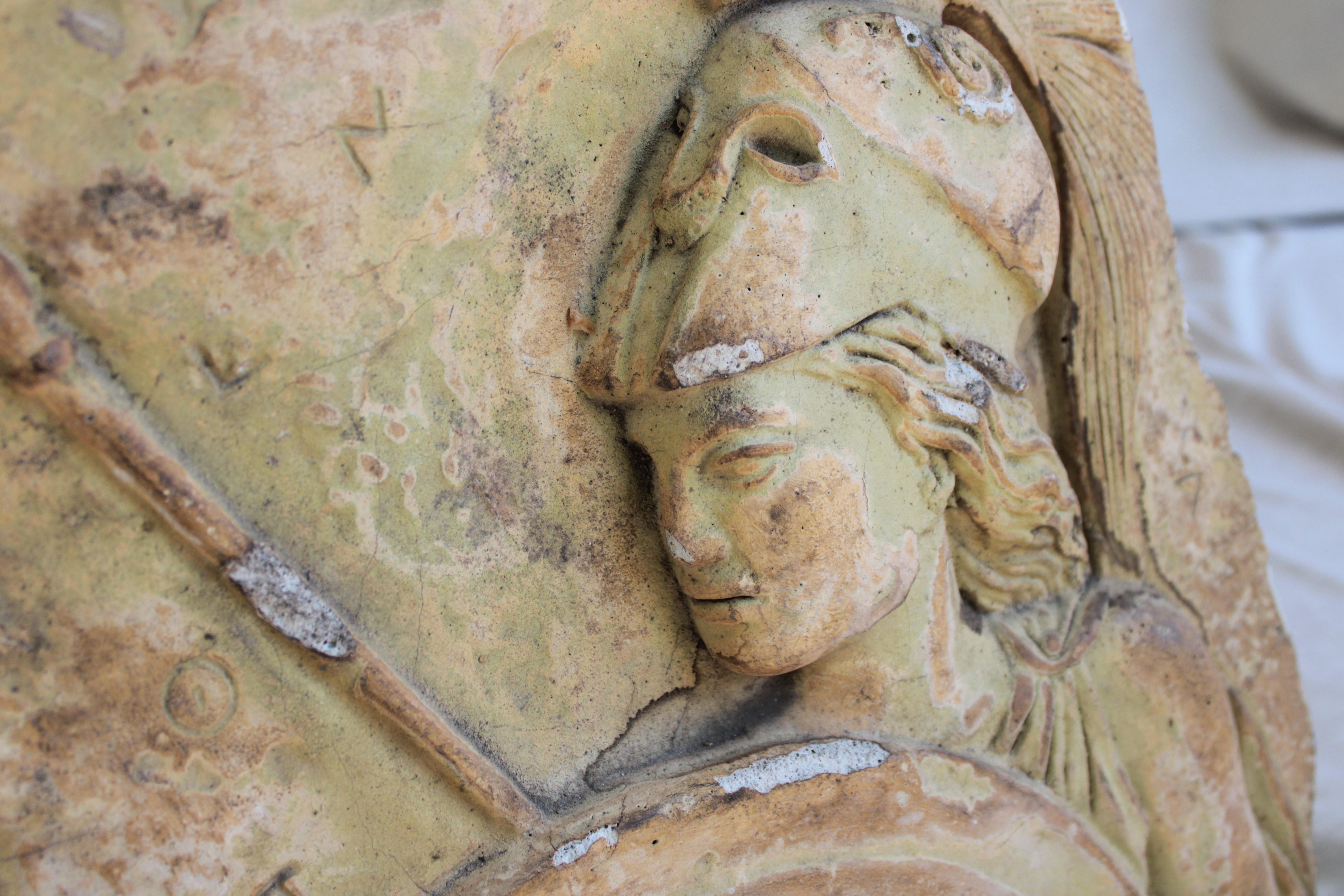 A bas-relief from the 20th century in Europe, that depicts a Roman soldier in a low-relief technique. It is made of plaster and finished with a patina to achieve a specific appearance.

In the 20th century, there was a renewed interest in