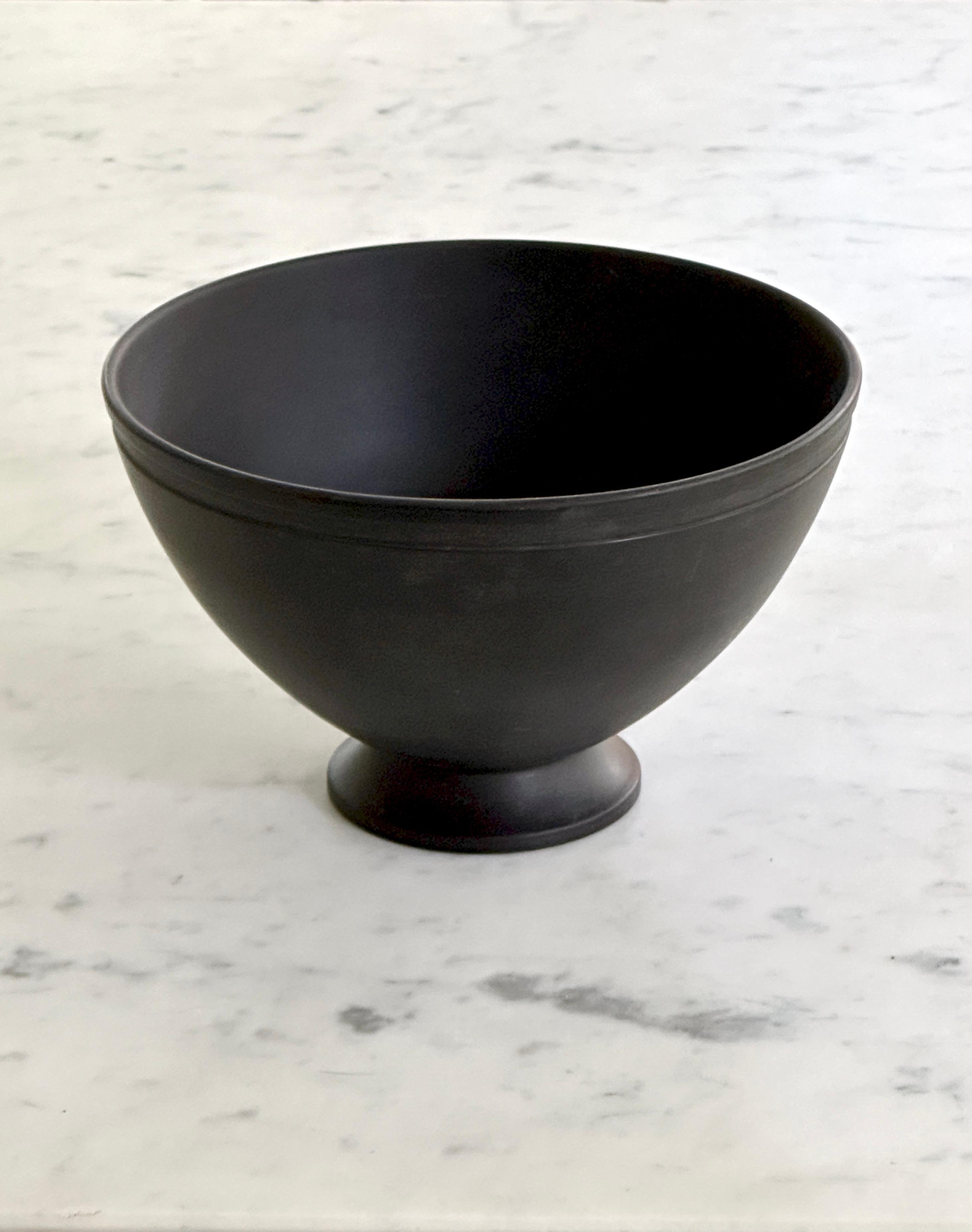 Cuenco con pie de basalto negro diseñado por Keith Murray para Wedgwood . El cuenco data de alrededor de 1935 y tiene el número de forma 3813. El cuenco mide aproximadamente 6 1/8 pulgadas de diámetro y mide 3 3/4 pulgadas de alto. En la parte