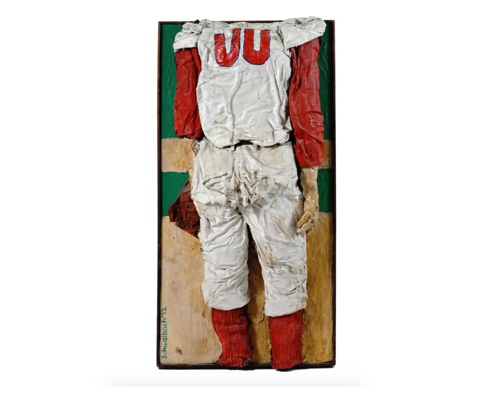 Mary Jo Schwalbach, American, born 1939, high relief mixed media, plaster and fabric, sculpture on board depicting the back of a baseball uniform. Signed and dated lower left. Framed. Mary Jo Schwalbach is an American artist and sculptor, known for