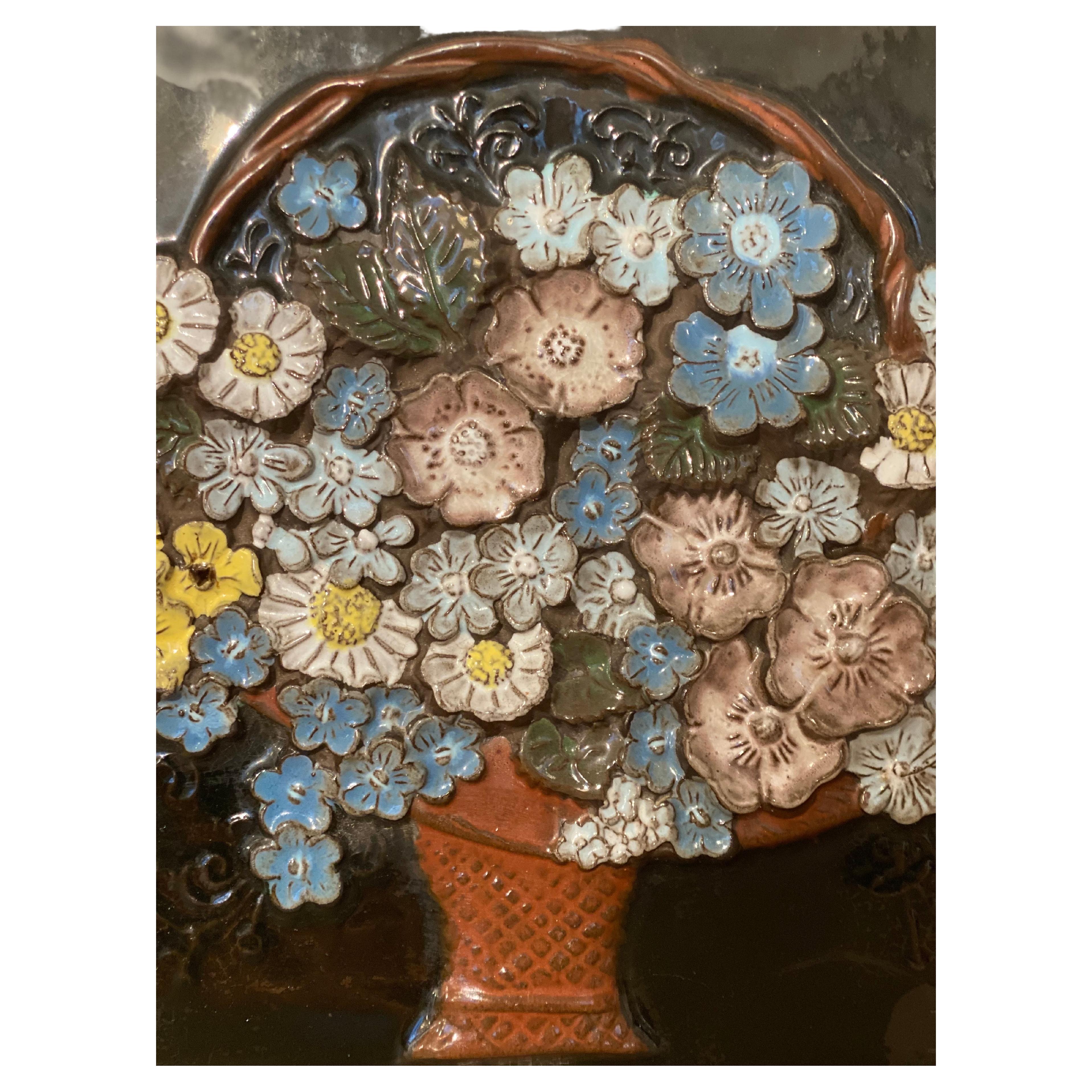 A vintage ceramic Jie Sweden wall plaque colorful flower tile to hang on the wall decorated with a flower basket designed by Aimo Nietosvuori for JIE Gantofta. In the beginning, he had his own factory, but from 1976, he worked as a designer of Jie