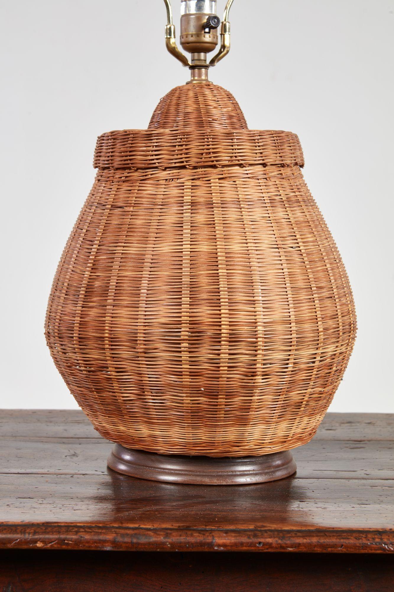 Lámpara de sobremesa adaptada a partir de una cesta de ratán indonesio de principios del siglo XX, de mimbre, con tapa desmontable, ahora sobre una base de madera torneada y cableada a través de la cesta con portalámparas y arpa.