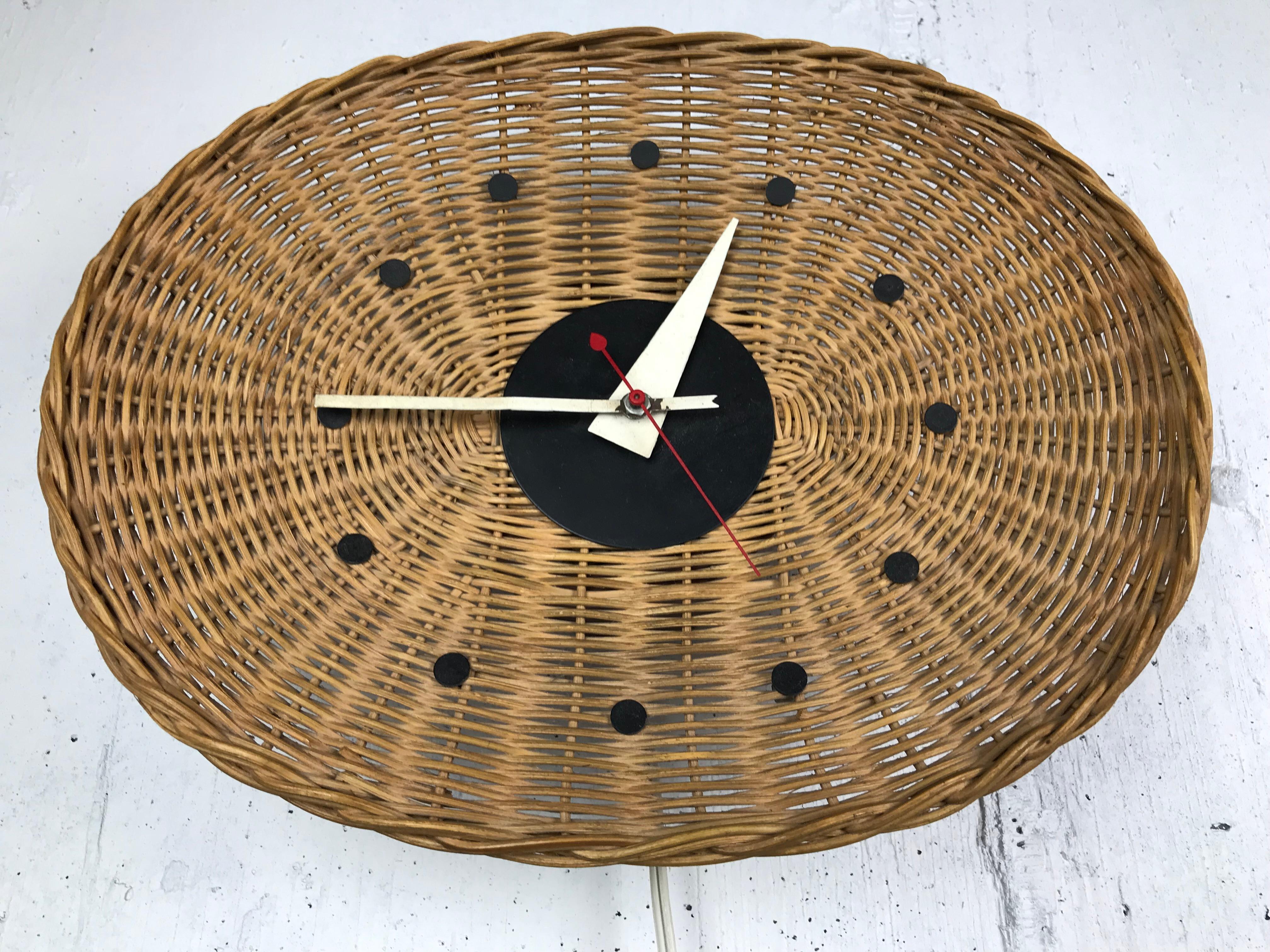 Modernist wicker 'basket' wall clock designed by George Nelson and Irving Harper for Howard Miller. Original condition - the clock works. Original hands with minor paint loss. Label present. 
Measures: 13