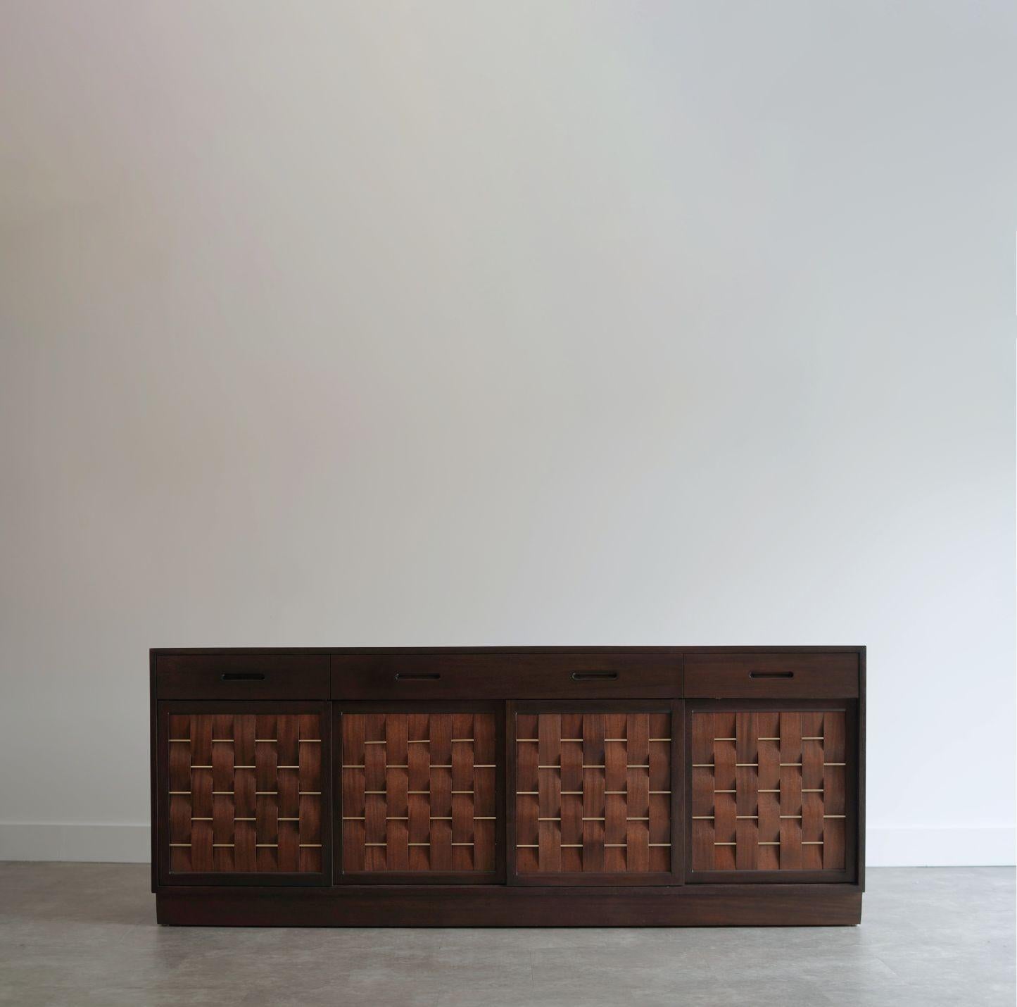 Very rare four-door mahogany credenza by Edward Wormley for Dunbar, featuring striking brass basket weave front panels. The center doors open to reveal a spacious shelf, while the side doors slide in to uncover a total of 10 drawers, offering