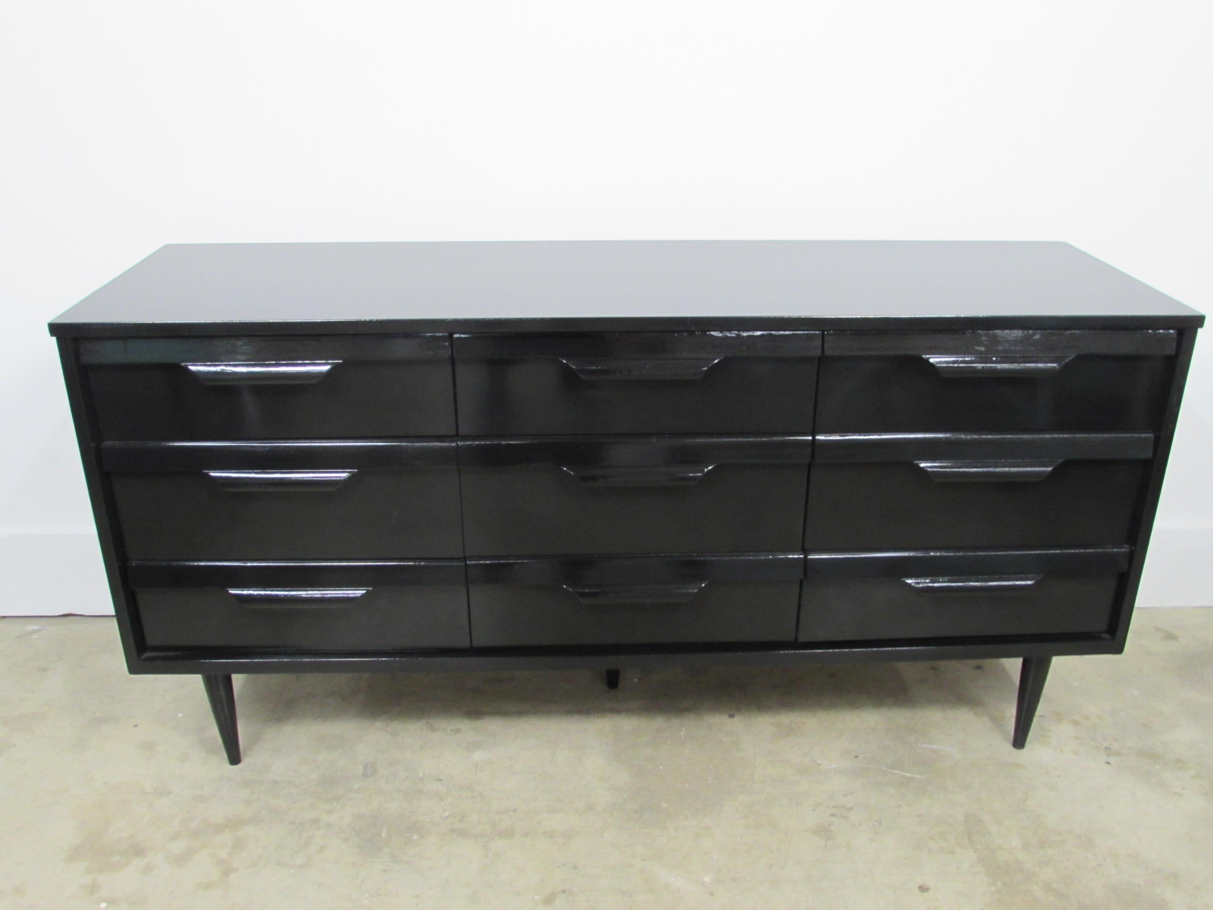 Bassett Mid-Century Modern credenza customized in-house in black lacquer with five stiletto legs and nine dovetail drawers.