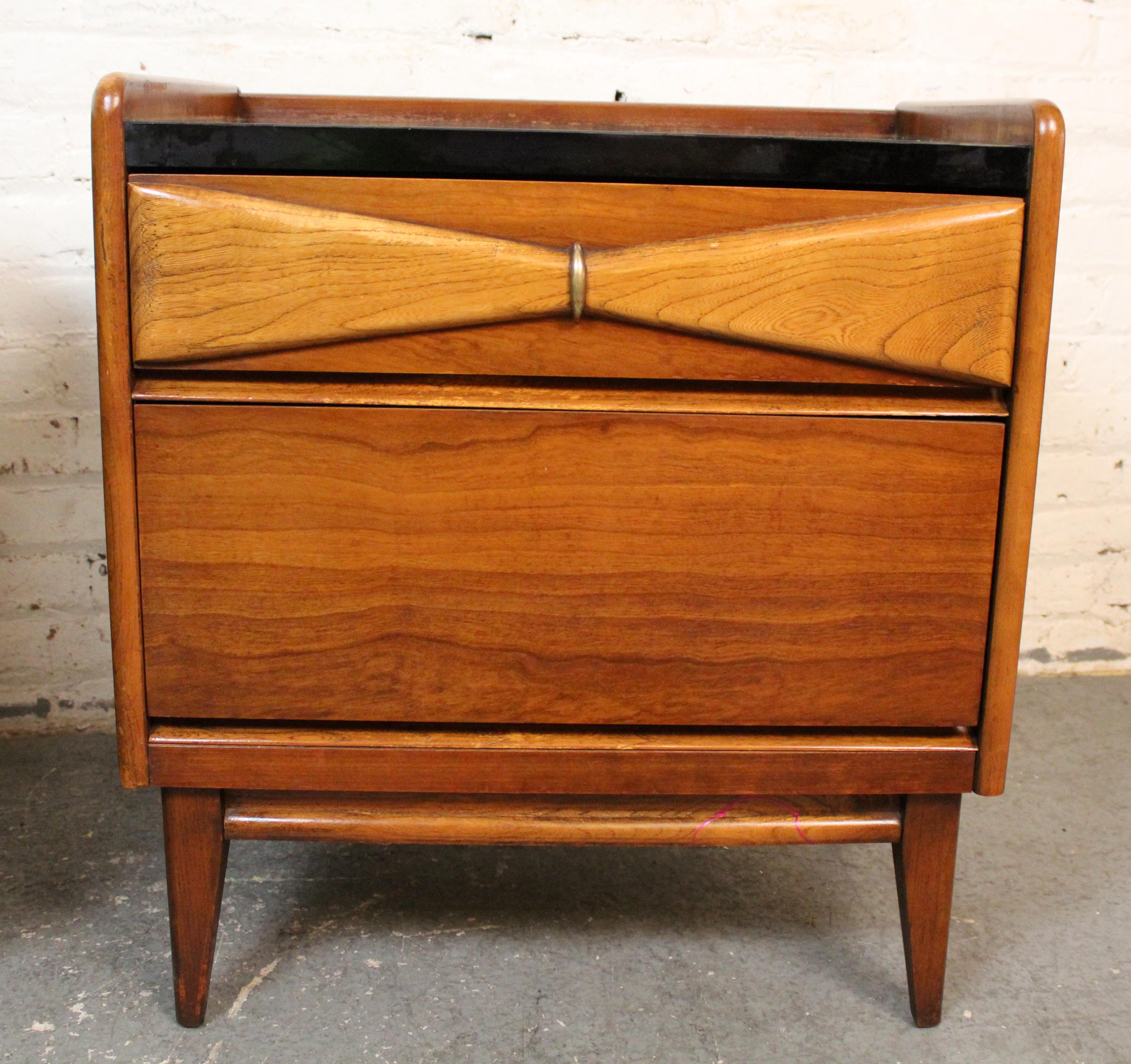 Sleek and sophisticated, this matching pair of Danique nightstands by Bassett features a rich blacktop finish contrasted by warm wood grain cabinetry. Each stand offers two drawers blending modern lines with mid-century inspiration. Ideal for adding