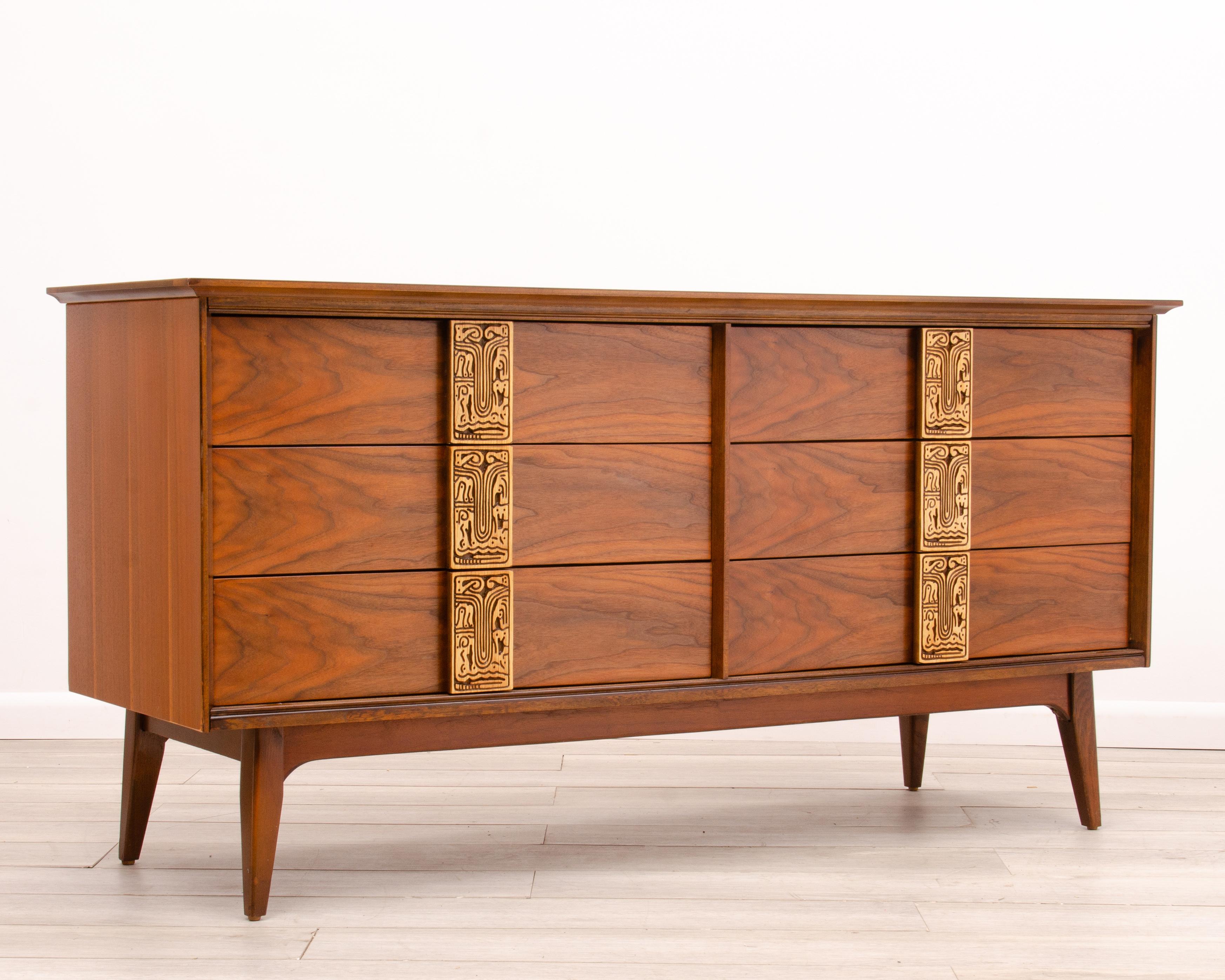 A Mid-Century Modern Bassett low dresser from the “Mayan” Collection. Circa 1960’s. The six drawer case has great size and proportion. The restored finish has more depth and clarity than the original factory finish.

The block carved tiki handles