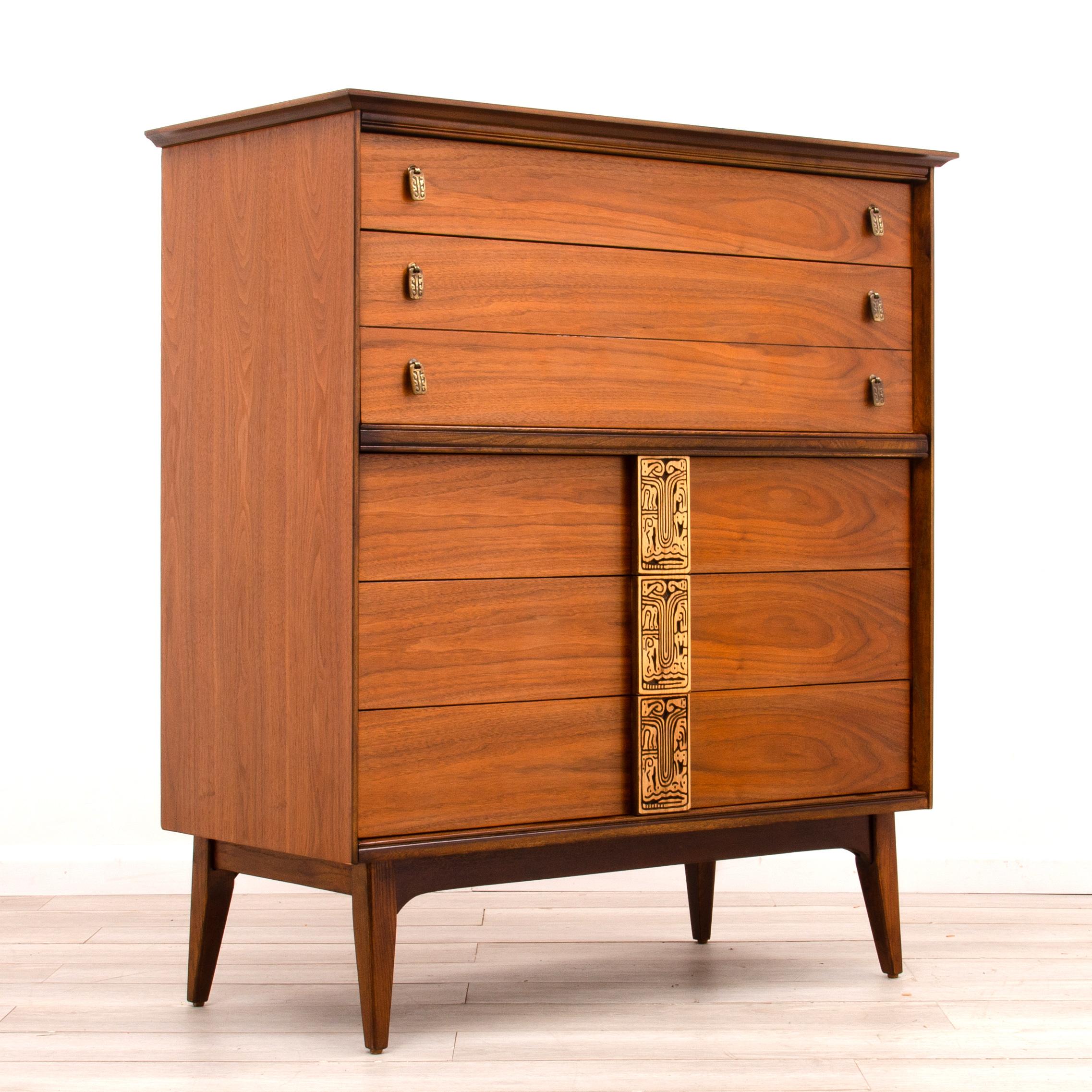 Vintage Mid Century Modern tall highboy dresser from the “Mayan” line by Bassett Furniture Company. The restored case has more depth and clarity to the finish than the original factory finish.
The block carved tiki handles provide a striking