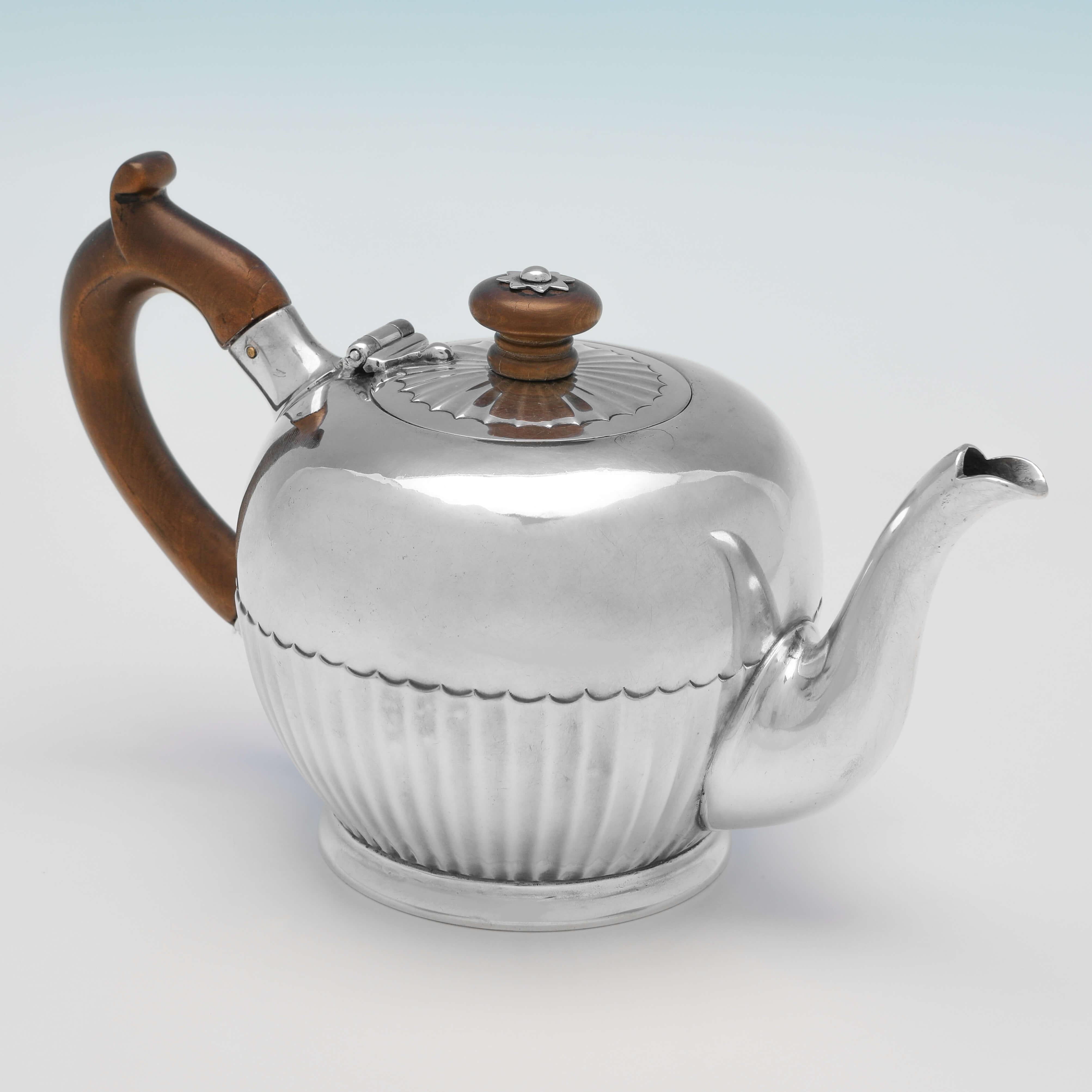 Hallmarked in London in 1783 by Henry Chawner, this charming, George III, Antique Sterling Silver Teapot, is 'bullet' shaped, featuring sunken fluting, and a wooden handle and finial. The teapot measures 4