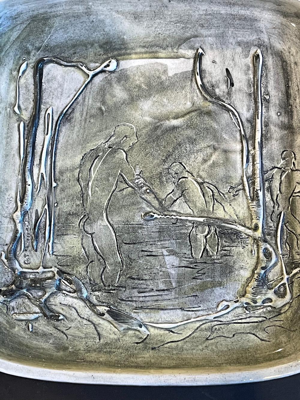 An especially rare example of Pat and Covey Stewart's ceramic work in Laguna Beach, California, this dish depicts a group of three nude male figures bathing in a marshy area along the California coast. Here, Pat Stewart used a squeeze bag technique