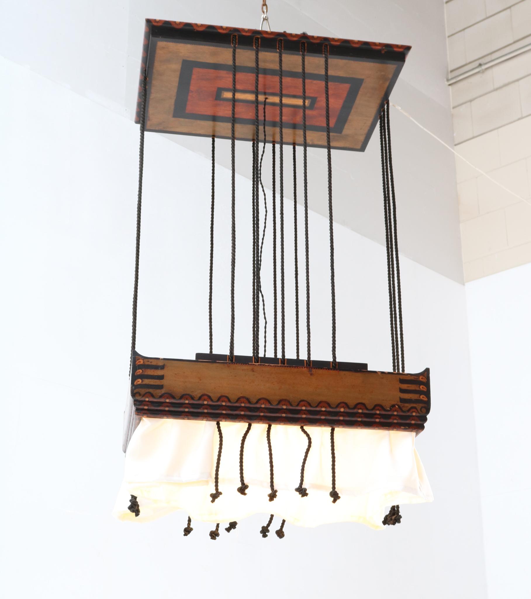 Magnificent and rare Art Deco Amsterdamse School chandelier.
Design by Louis Bogtman.
Striking Dutch design from the 1920s.
Original batik wooden frame with ceiling rose, silk shade and black lacquered cords.
Rewired with one original socket for