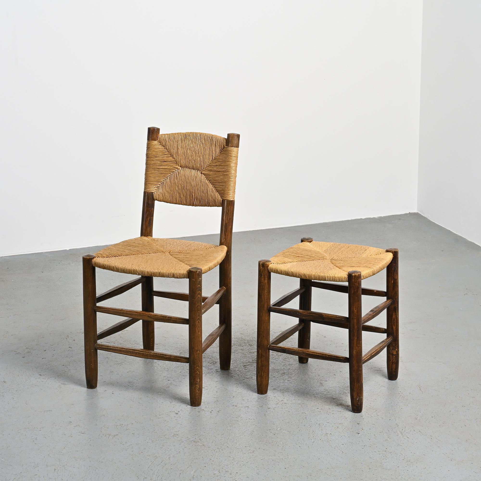 
Conjunto compuesto por una silla Bauche n°19 y un taburete Bauche, diseñados por Charlotte Perriand y fabricados por la Maison Sentou en la década de 1950.

La silla tiene un armazón de fresno macizo con cuatro patas redondeadas unidas por