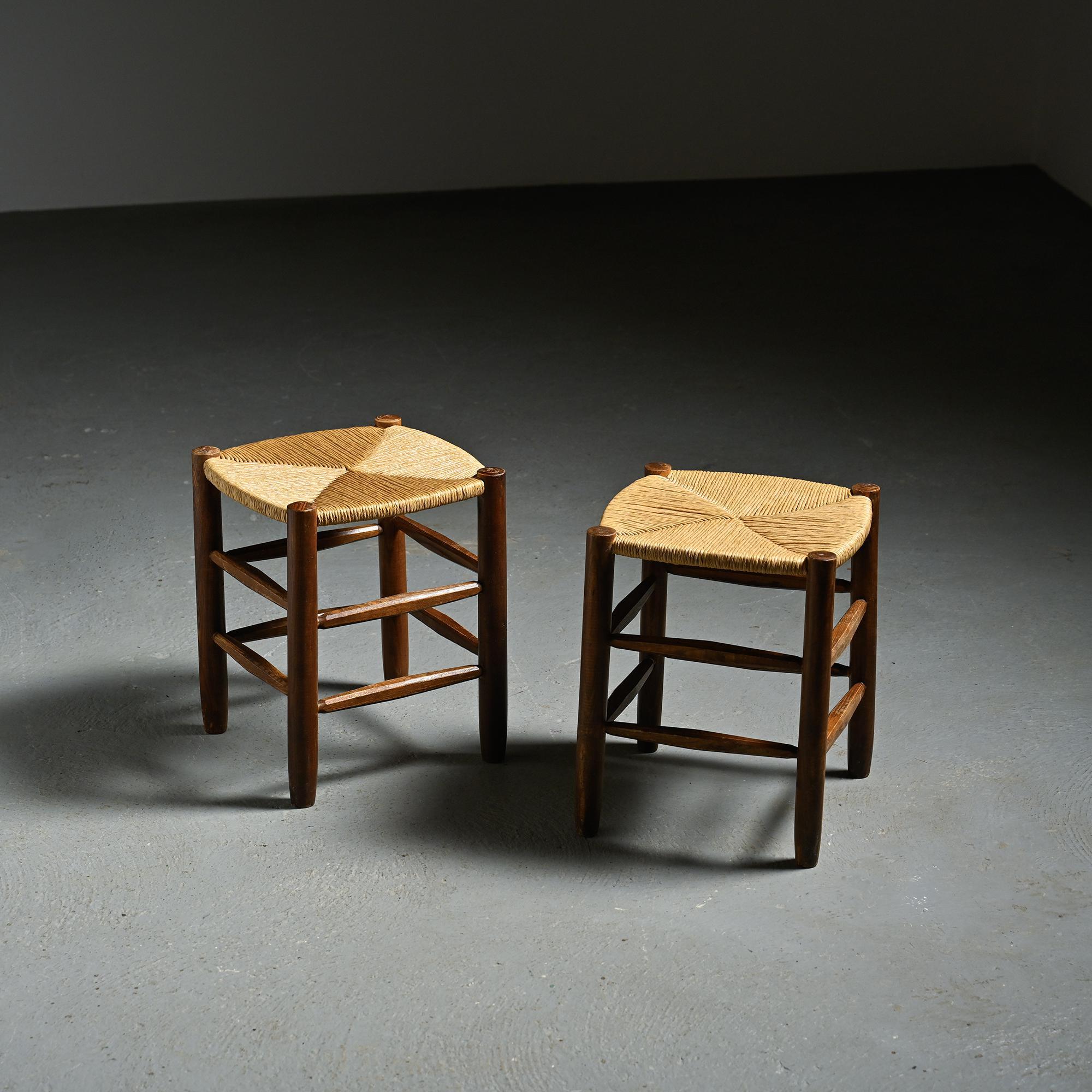 Designed in the 1950s by Charlotte Perriand, these two stools belong to the Bauche n°19 model, published by Steph Simon. The solid ash structure features four rounded legs joined by stretchers, supporting a handwoven straw seat restored to its