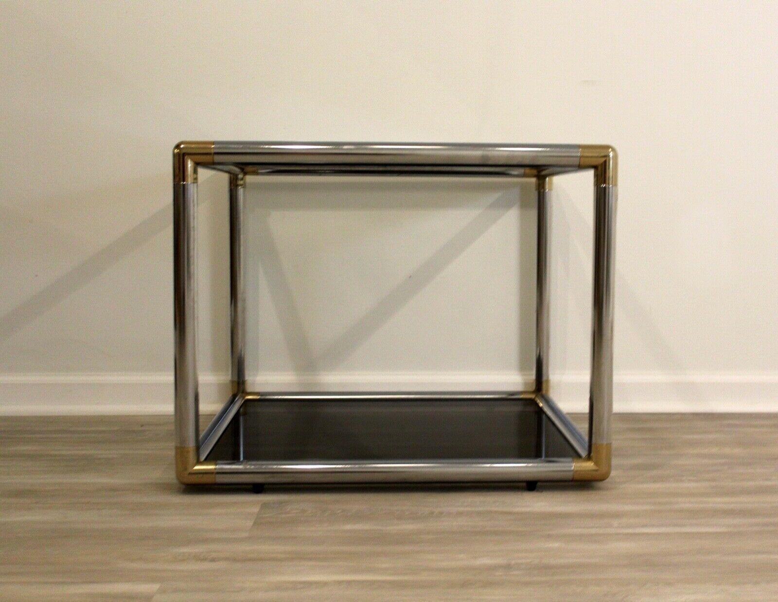 This tubular chrome side or end table is reminiscent of the mid century style of Baughman. The cube table has brass caps on all four corners which support the black and clear glass on bottom and top. An amazing mid century modern piece and in very