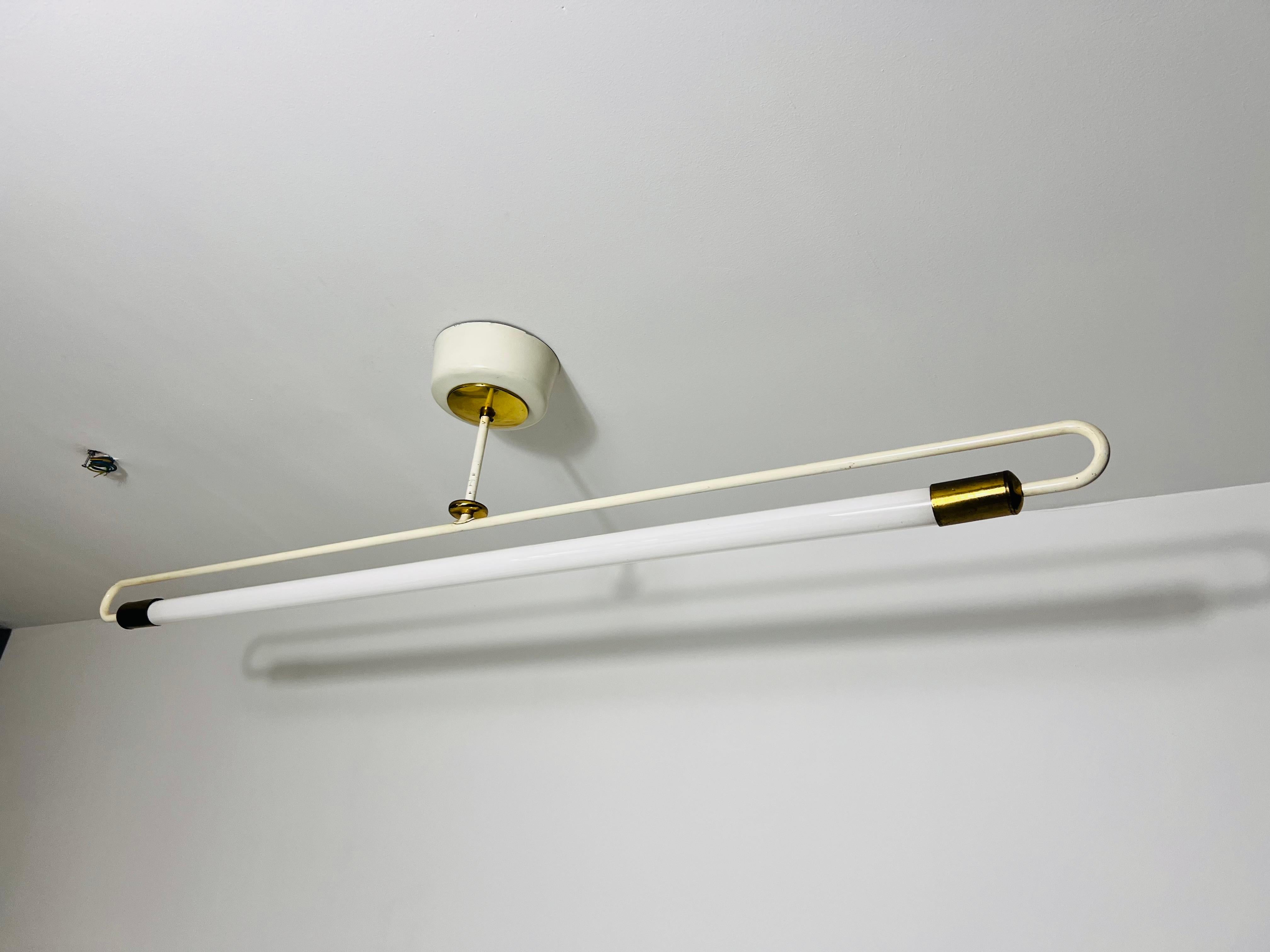 This striking Bauhaus ceiling lamp, crafted by Kaiser & Co. in the 1950s, is a perfect embodiment of the iconic Bauhaus aesthetic. Featuring a sleek and elongated design, it combines brass and metal elements to create an industrial yet elegant look