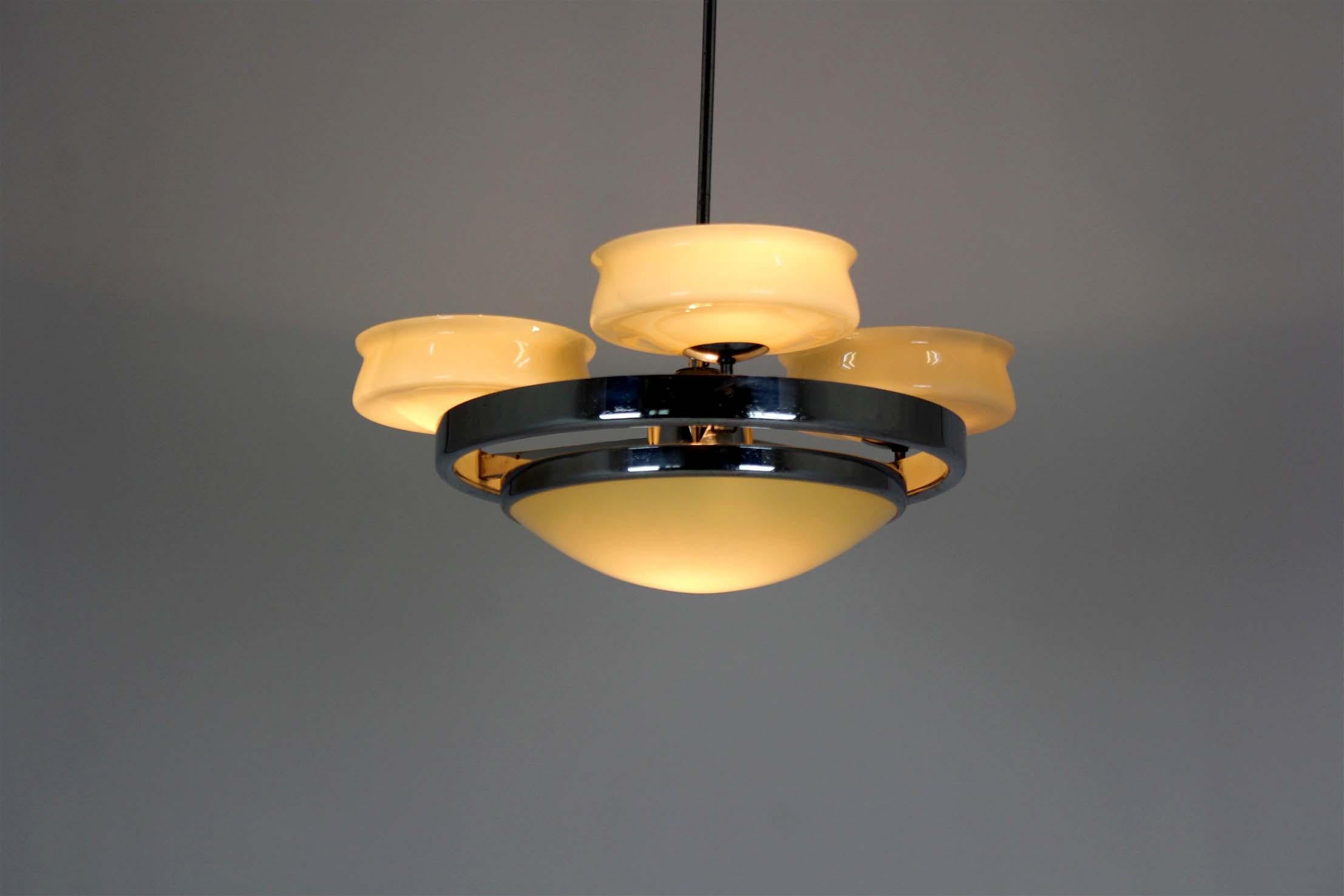 
A vintage Bauhaus-style chandelier from the 1930s–1950s, made of chrome-plated metal and yellow ribbed glass. It has a clean, geometric design typical of the Bauhaus movement, combining simple shapes with practical function. The yellow glass shades