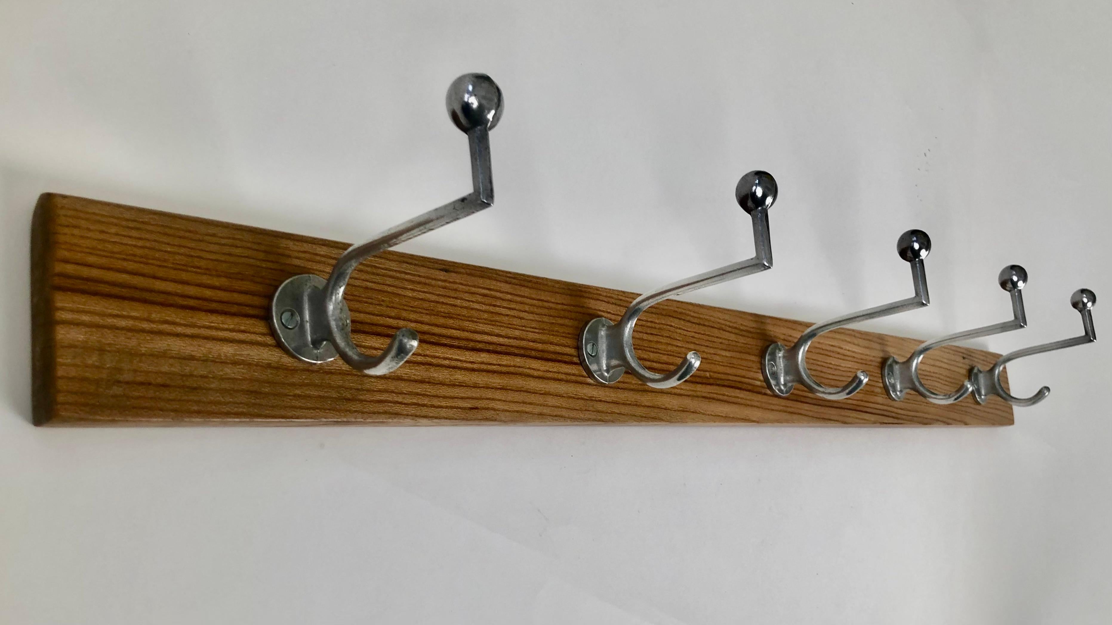 Un bellissimo set di cinque appendiabiti Bauhaus in alluminio.
Tutti e cinque i ganci sono montati sulla tavola posteriore originale in noce.
Il legno era originariamente sigillato con gommalacca  ed è stato rinfrescato.