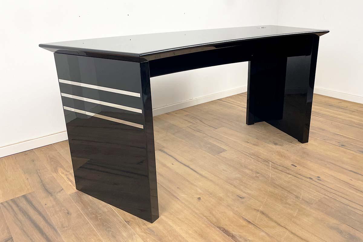 Impressive Bauhaus desk in elegant black piano lacquer. The high-gloss stainless steel strips have been polished and give the desk a very special grace. The entire desk has been restored and hand polished to a high gloss - a fantastic piece of
