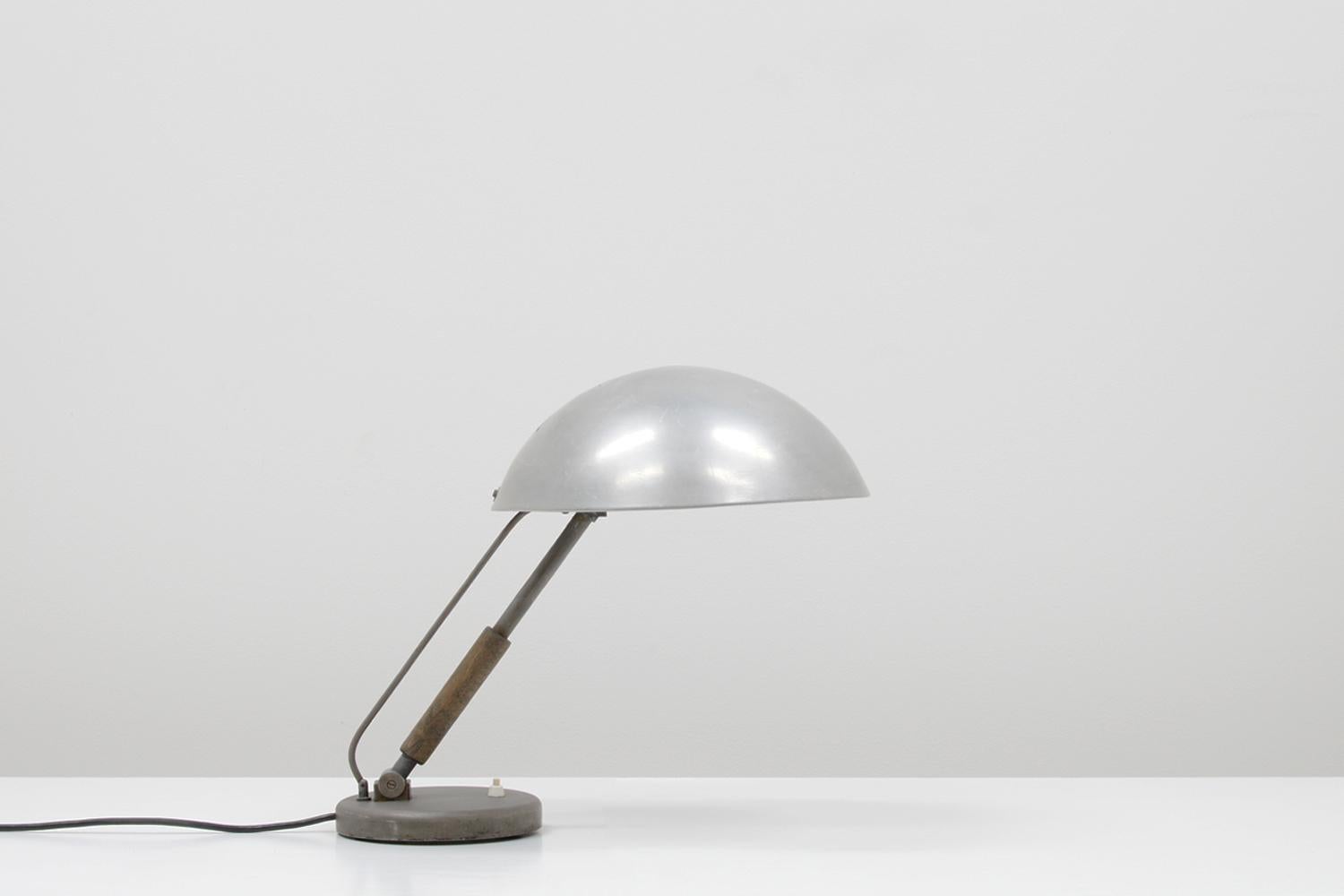 Bare metal bauhaus desk light by Karl Trabert for Schanzenbach und Co. GmbH, 30s Germany. Adjustable shade, wooden handle and bakelite E27 socket. Nice patina and in good vintage condition. 

 